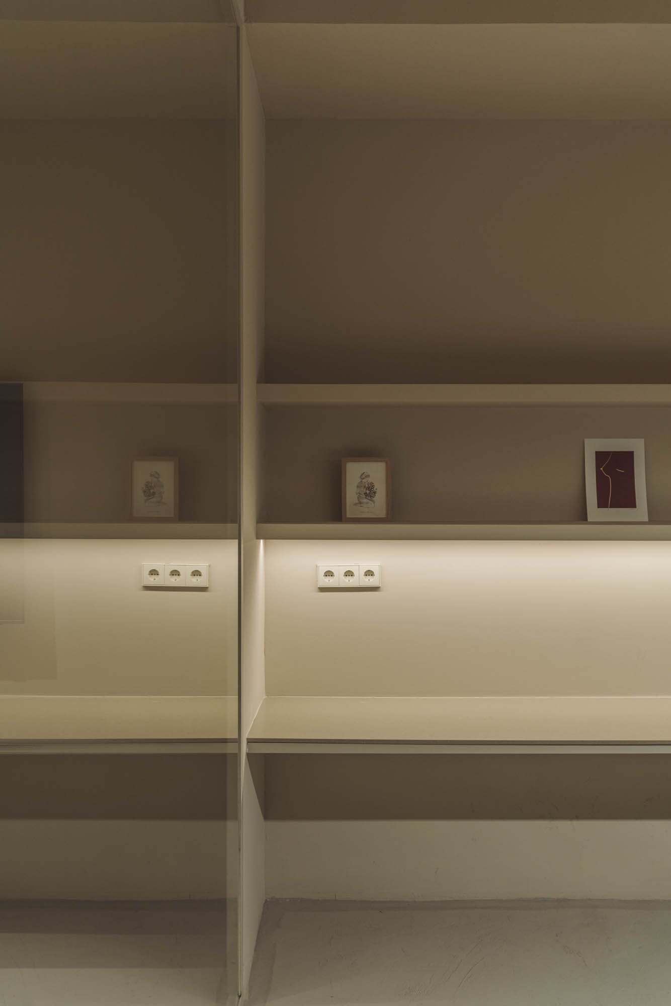 Estantería con dos niveles y tres cuadros decorativos, una luz suave y un enchufe eléctrico en la parte inferior