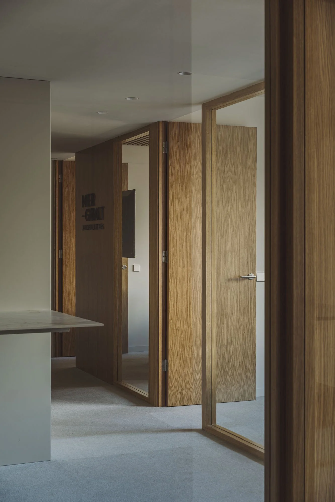 Pasillo en un interior con puertas de madera, uno de los cuales tiene un espejo y uno tiene un televisor.