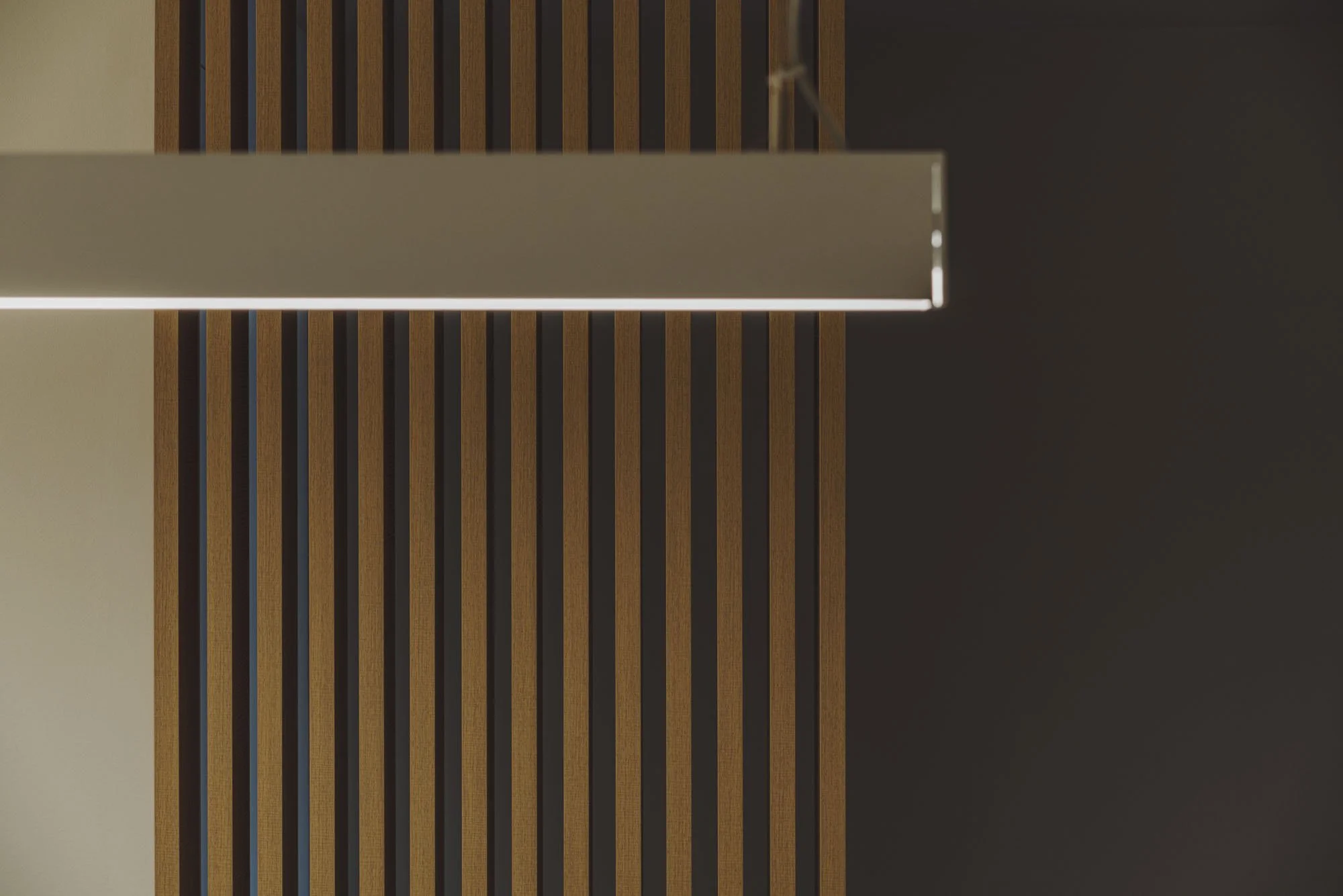 Lámpara rectangular suspendida sobre paredes de madera y fondo oscuro.