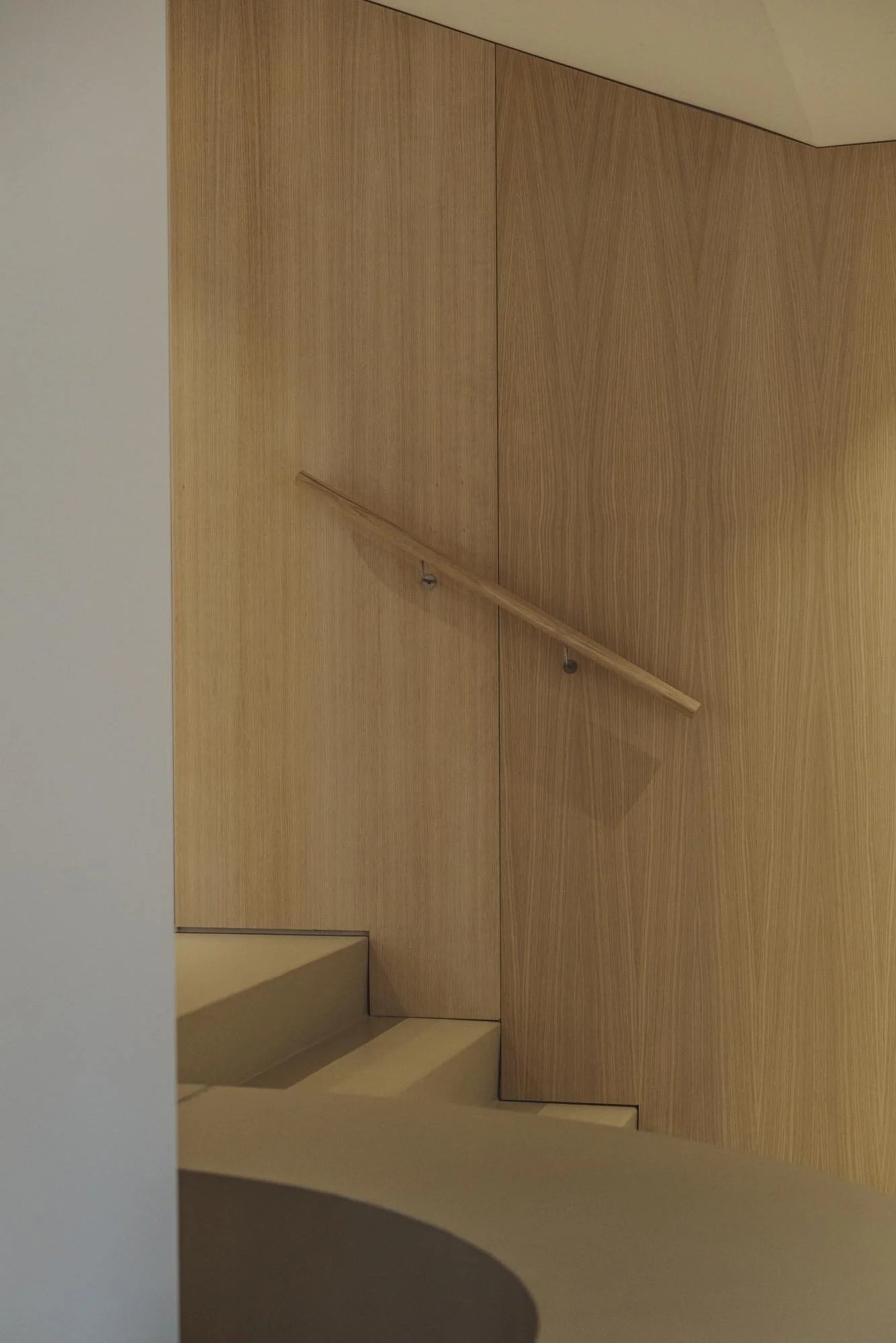 Escalera con barandilla de madera y paredes de madera en un interior moderno.