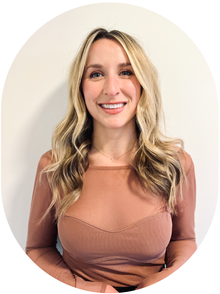 Portrait of a smiling woman with long blond hair, wearing a tan long-sleeve top, standing against a white background with a black curved design element.
