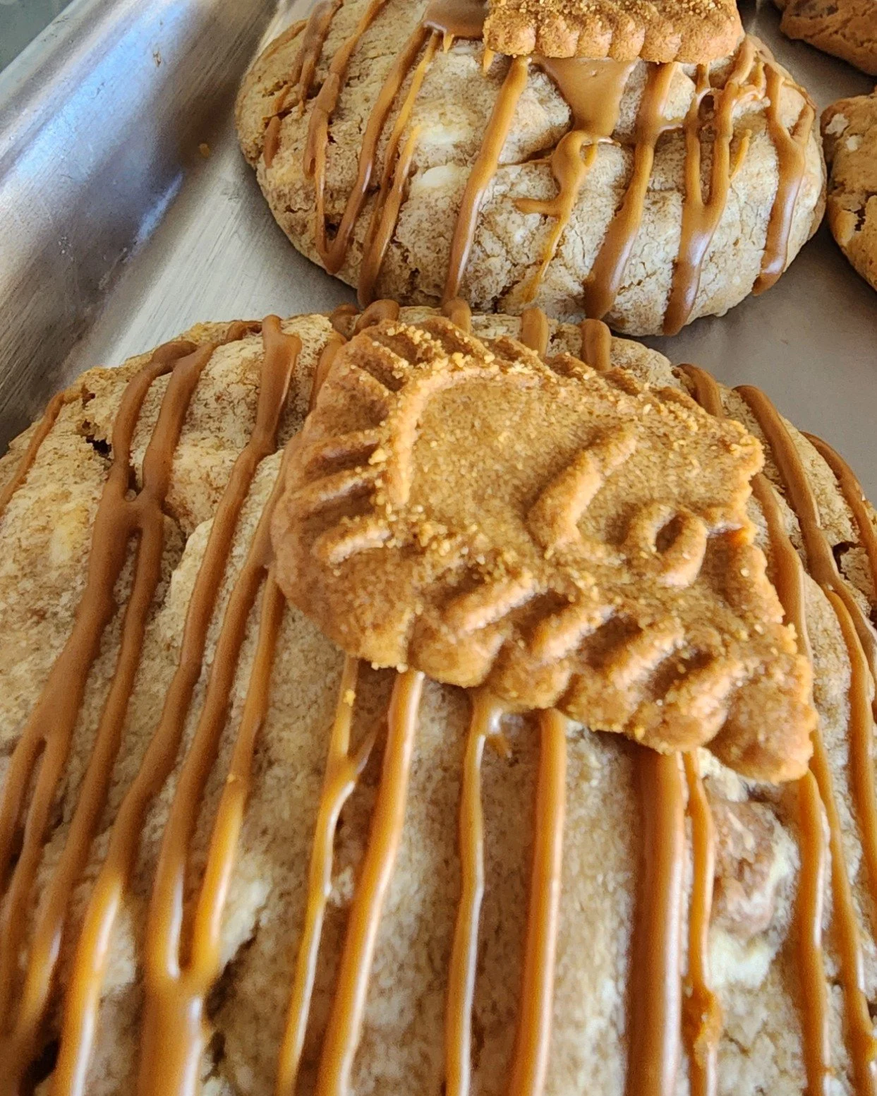 Close-up of cookies decorated with caramel drizzle and ghost-shaped cookie with the word 'BOO' written on it.