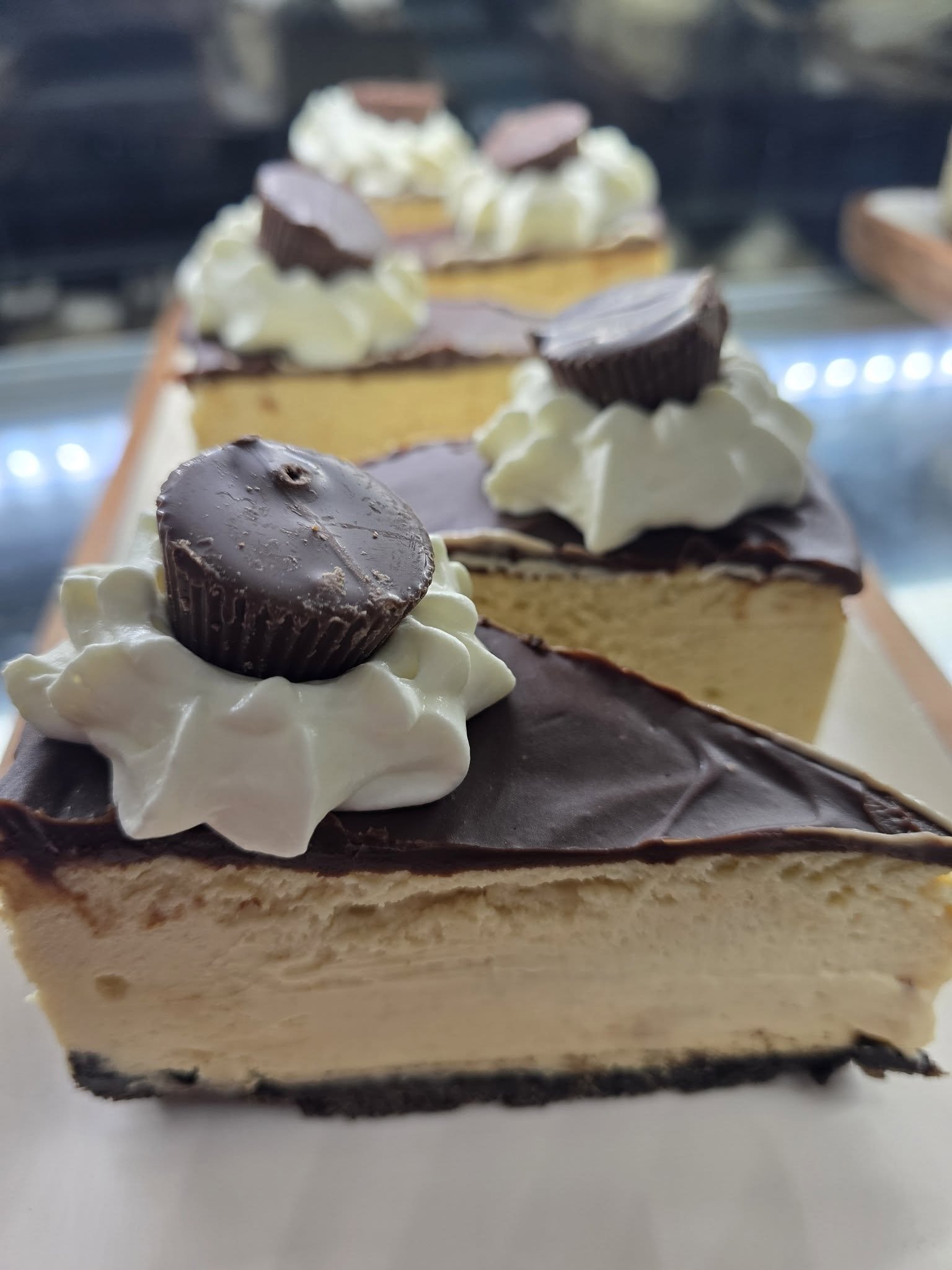 Slices of cheesecake topped with whipped cream and mini chocolate cups.