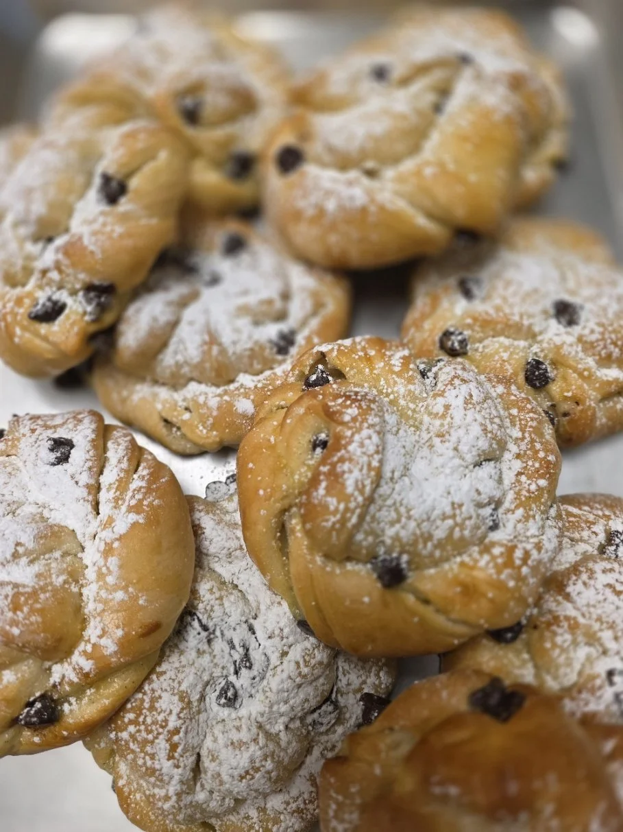 Close-up of chocolate chip cookies dusted with powdered sugar on a tray.