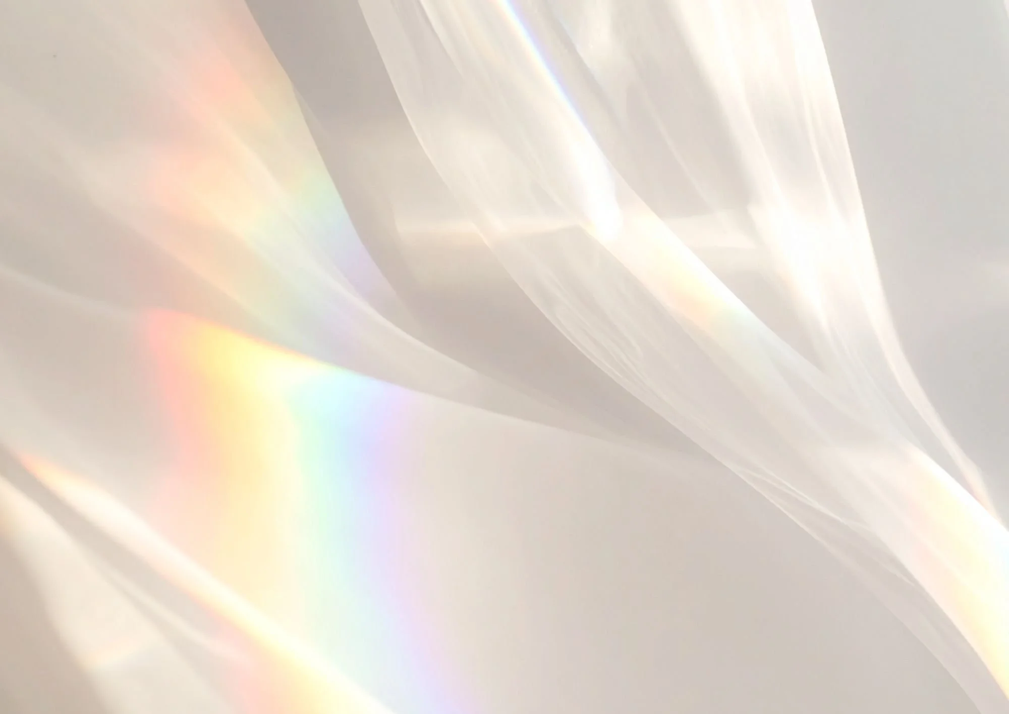 Helle, schimmernde Lichtreflexe auf einer transparenten Oberfläche, die Regenbögen in Pastellfarben erzeugen.