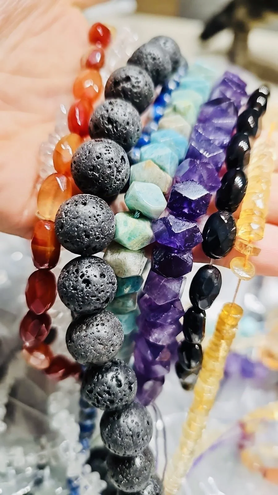 Verschiedene bunte Perlenketten in einer Hand gehalten.