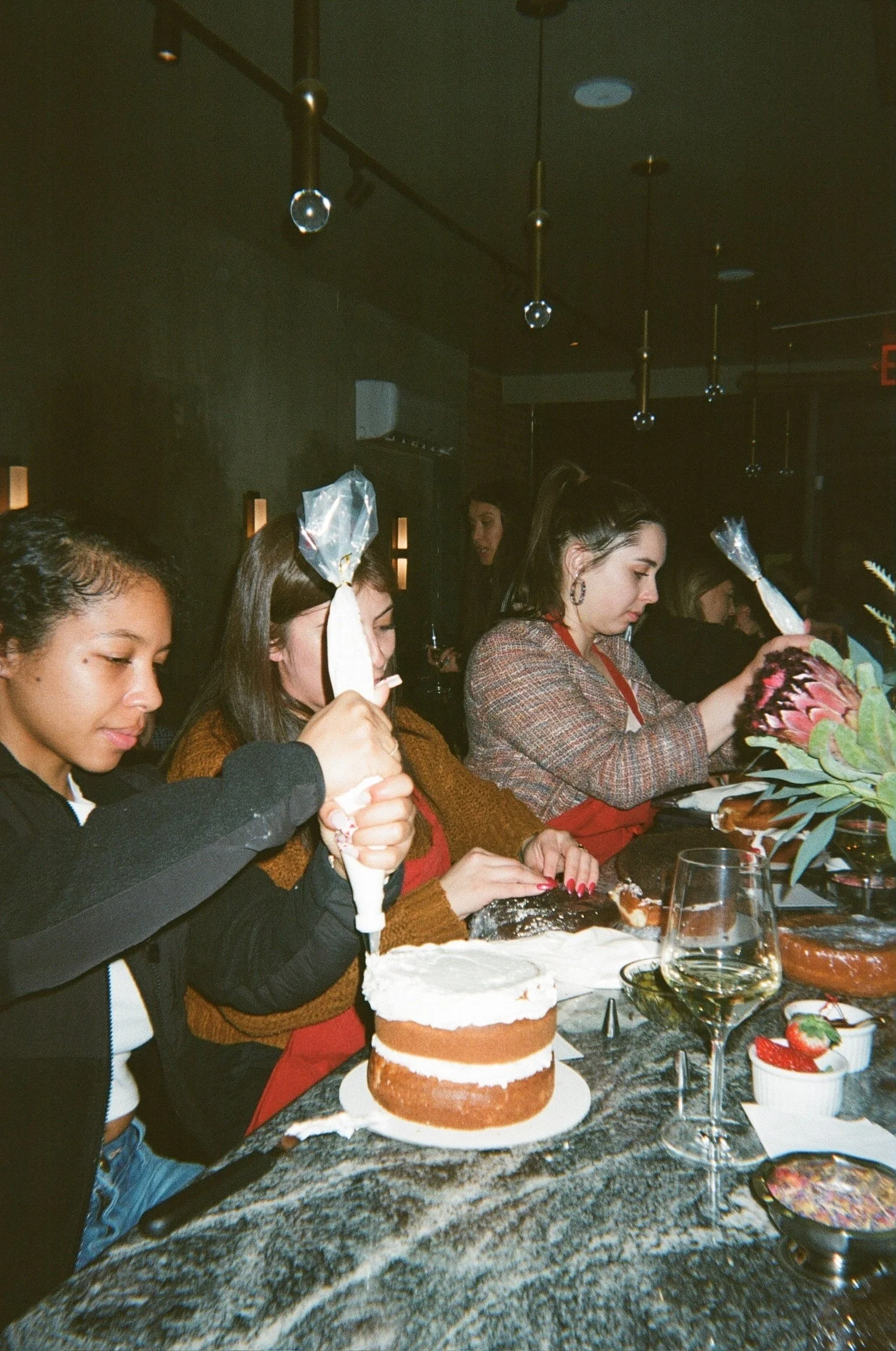 Group of women decorating a wedding cake at a celebration.