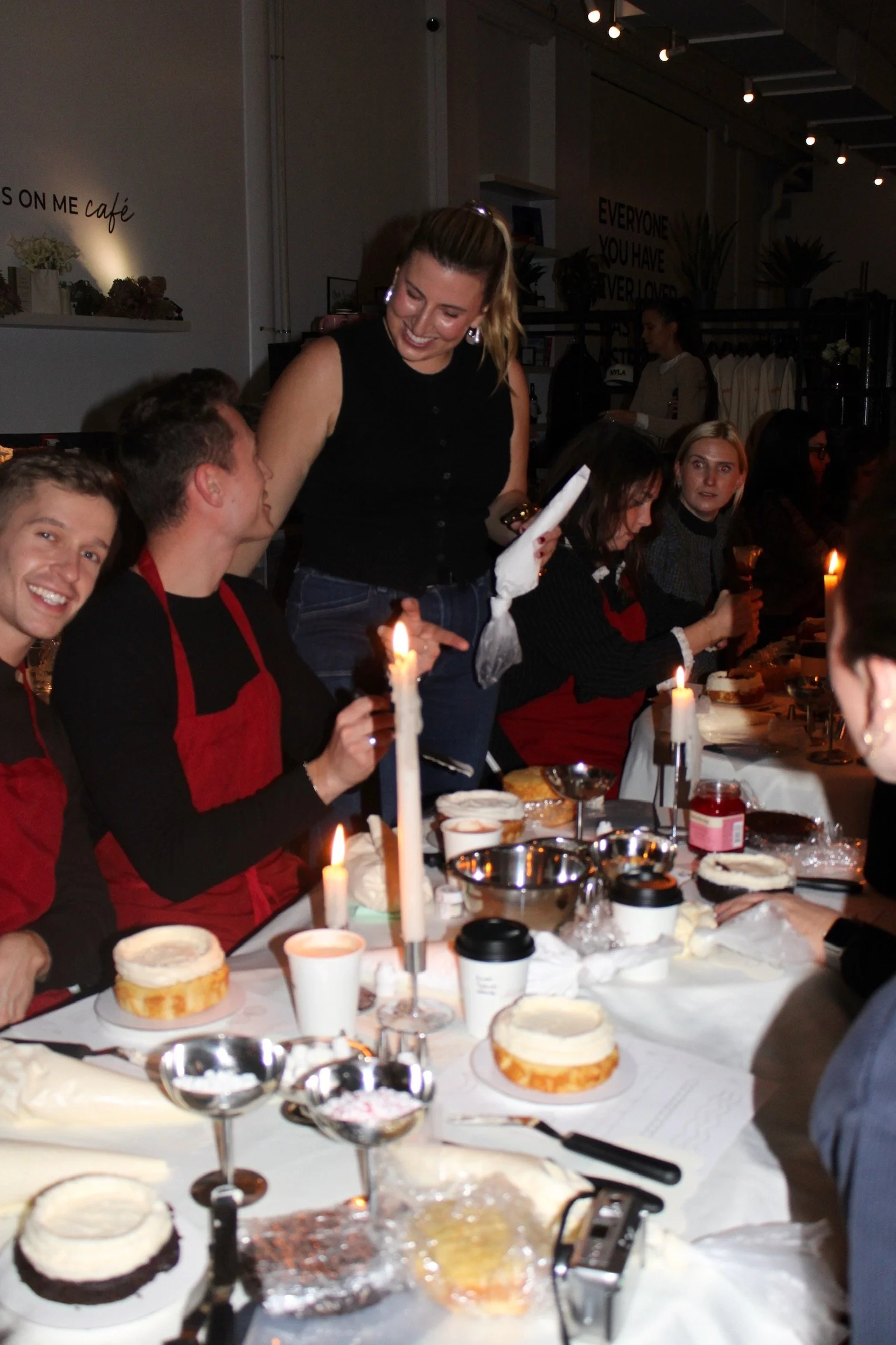 People celebrating a birthday with cake and candles at a table in a cozy, dimly-lit restaurant or bakery.