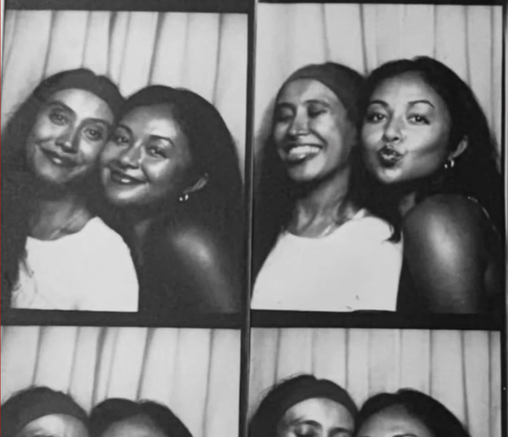Four black-and-white photo booth portraits of two women smiling and making faces, standing close together in front of a curtain background.