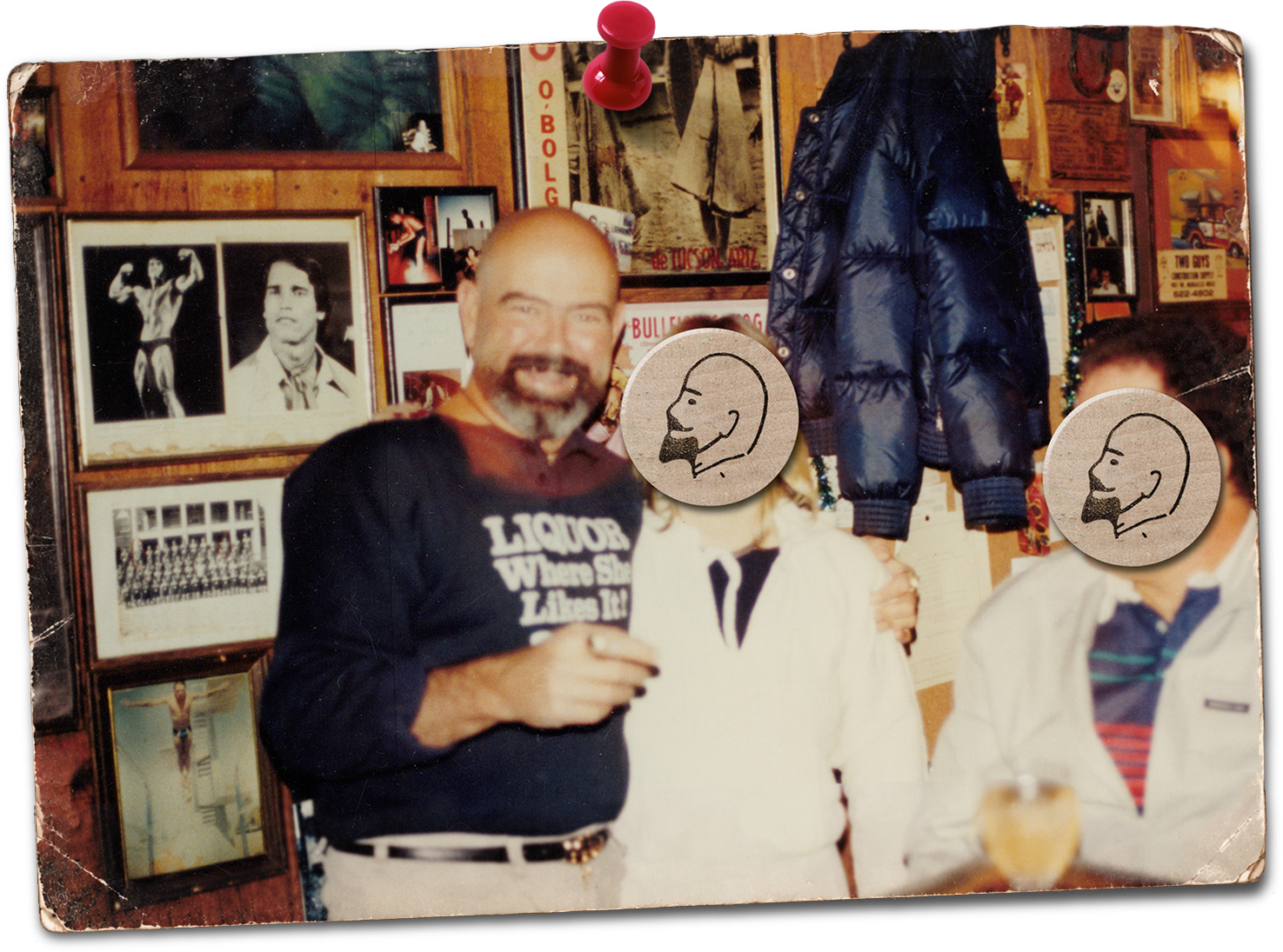 A photo of Jim "God" Anderson and his worshippers in one of his bars. Jim is wearing a black shirt with white text, and both the woman and man are wearing white tops. The wall is decorated with photographs, paintings, and memorabilia.