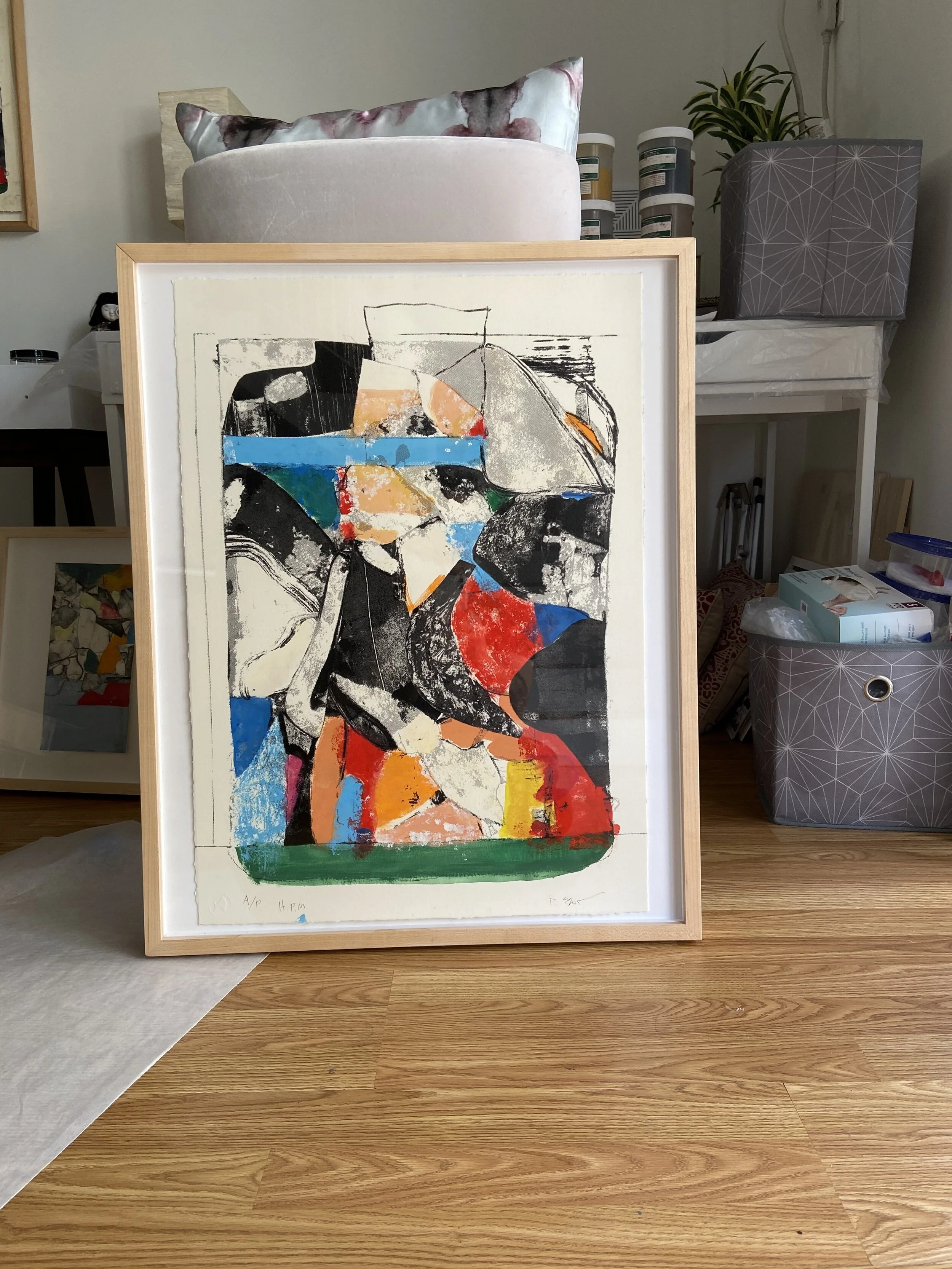 An abstract colorful painting with various shapes and lines, leaning against a chair on a wooden floor.