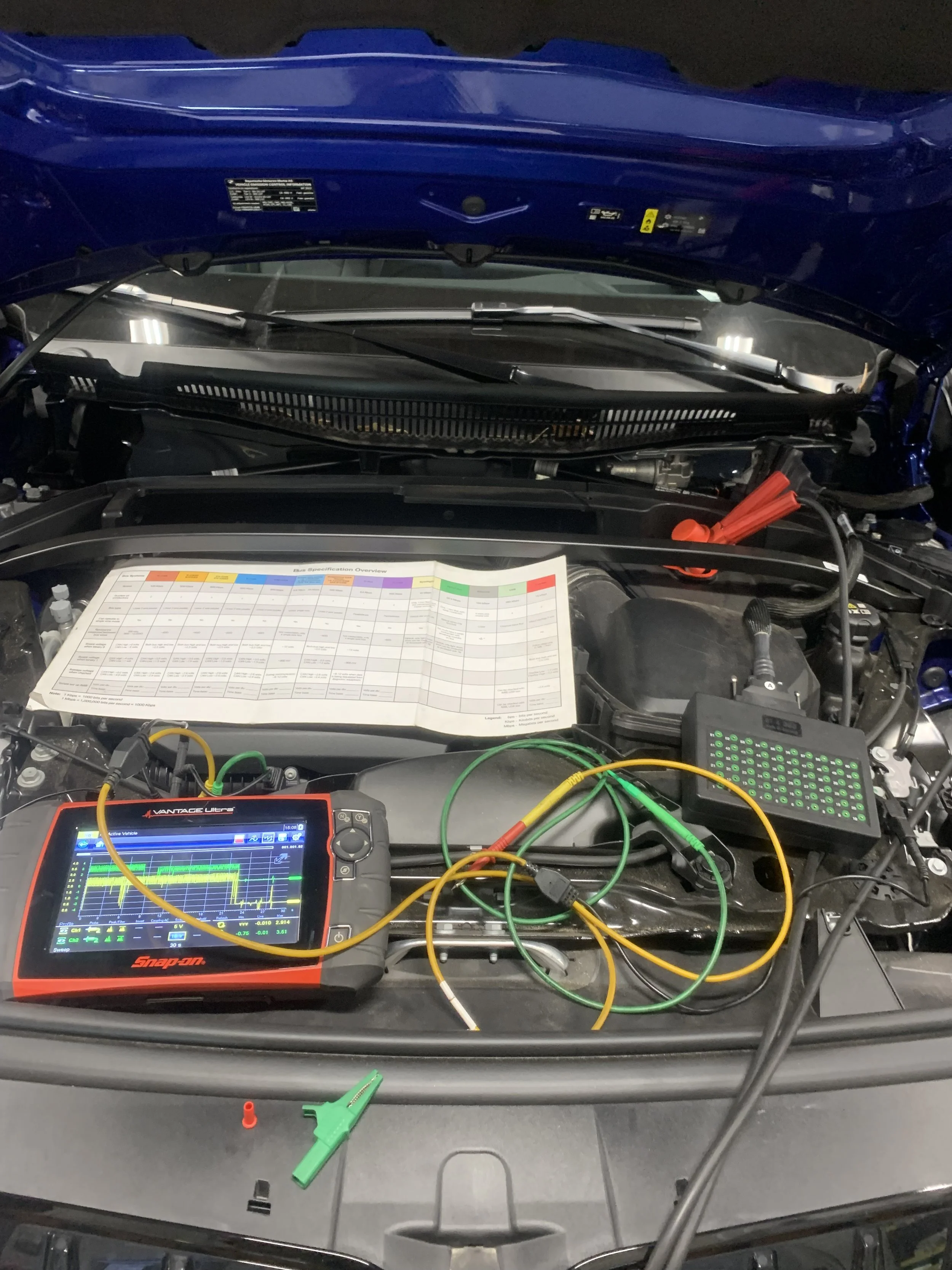 The image shows the engine bay of a vehicle with diagnostic tools and wiring connected, including a Snap-on diagnostic scanner.