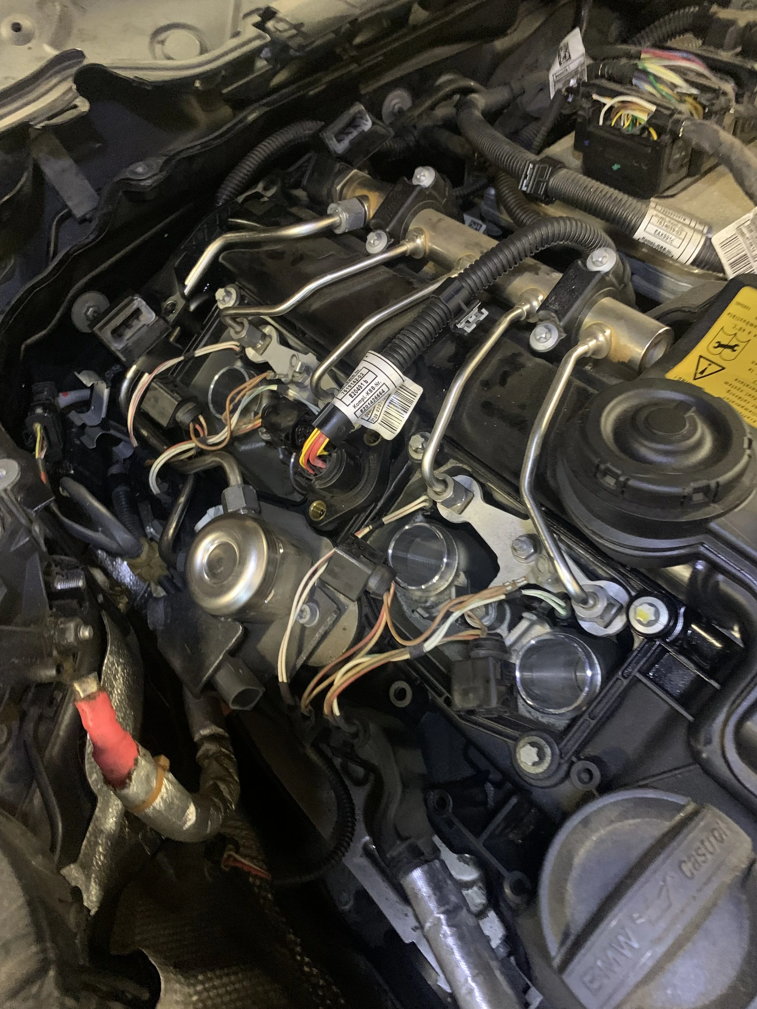 Close-up view of a car engine with various components, wires, and metal pipes visible.