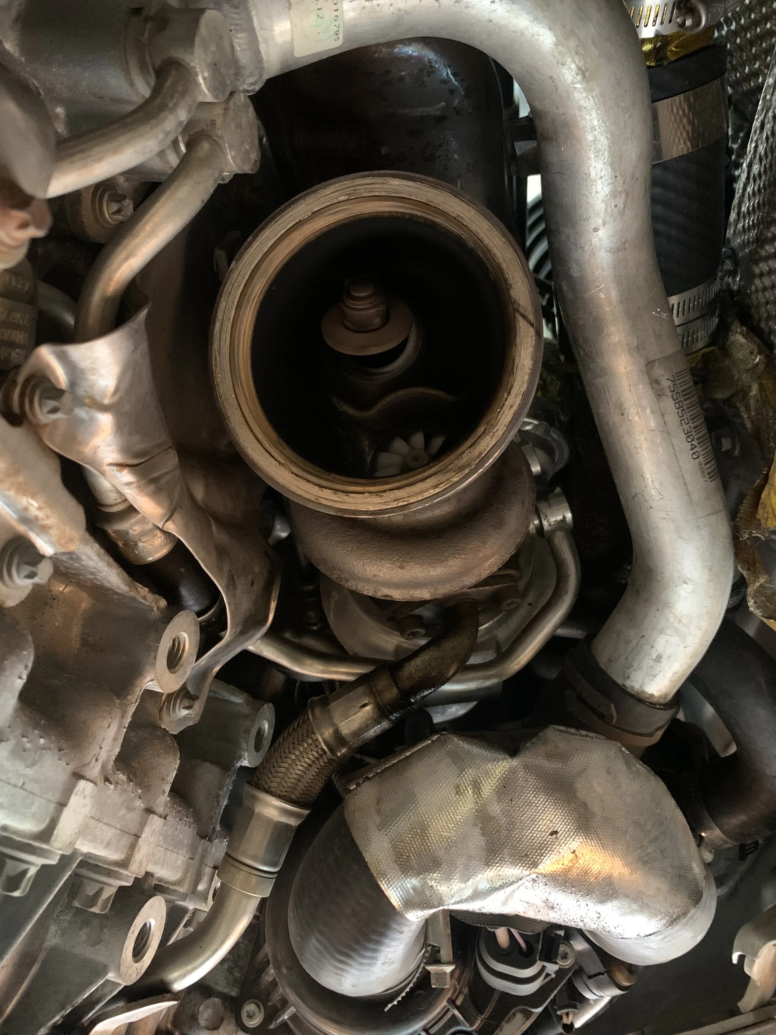 Close-up of an engine's internal components, showing metallic pipes, a large central circular part, and various metal parts and fasteners.
