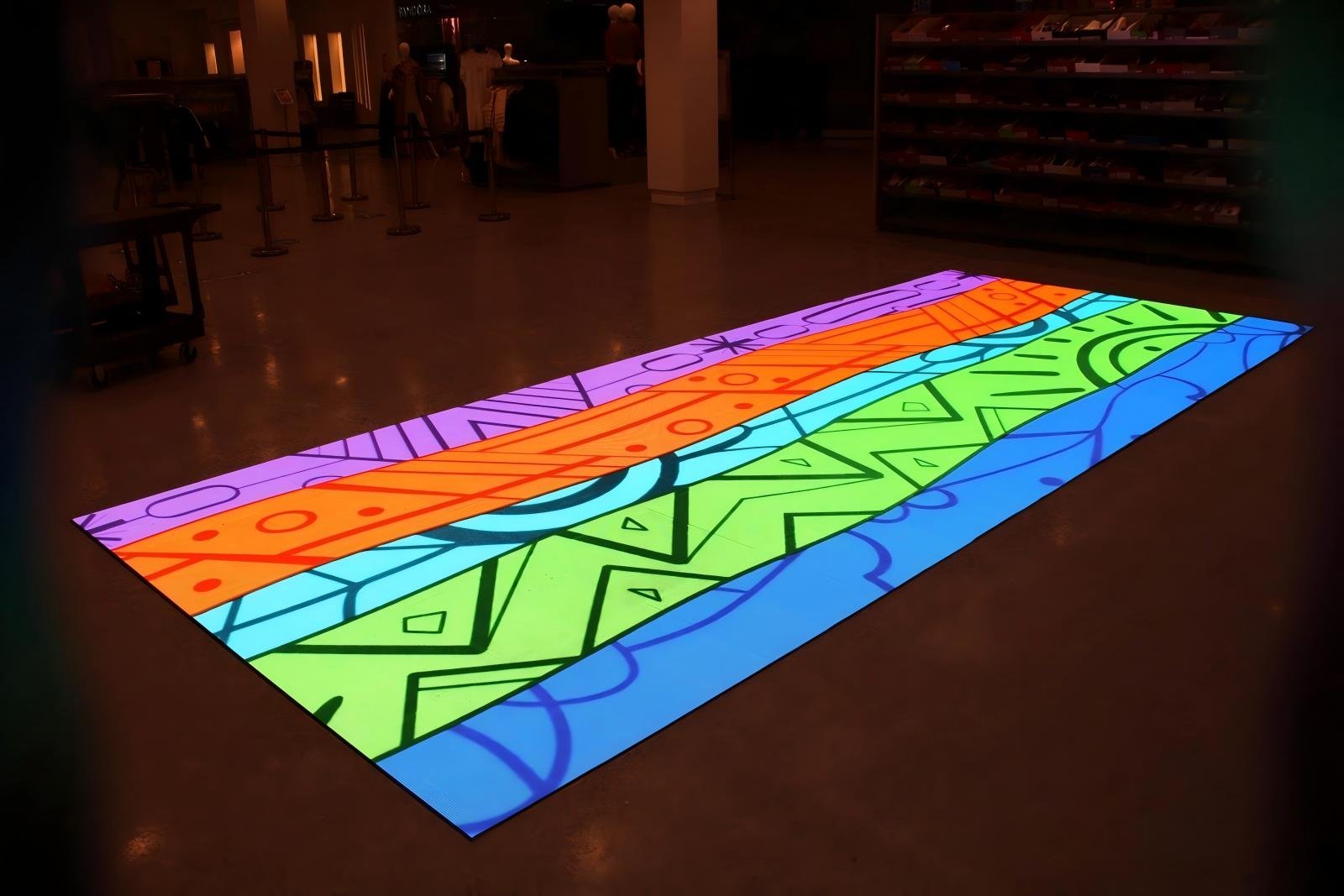 Colorful interactive floor with geometric patterns at an indoor space, possibly a museum or exhibit area.