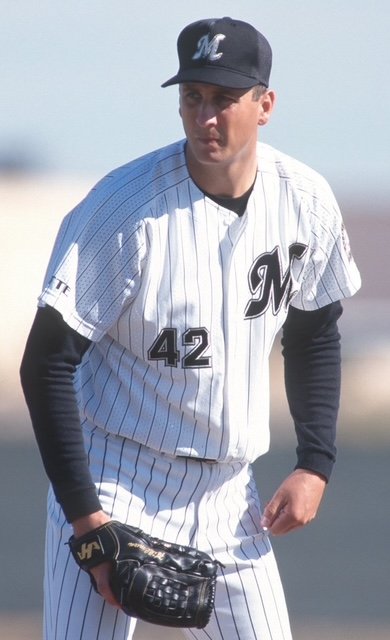A baseball player in a uniform with the number 42, wearing a black cap, practicing on the field.