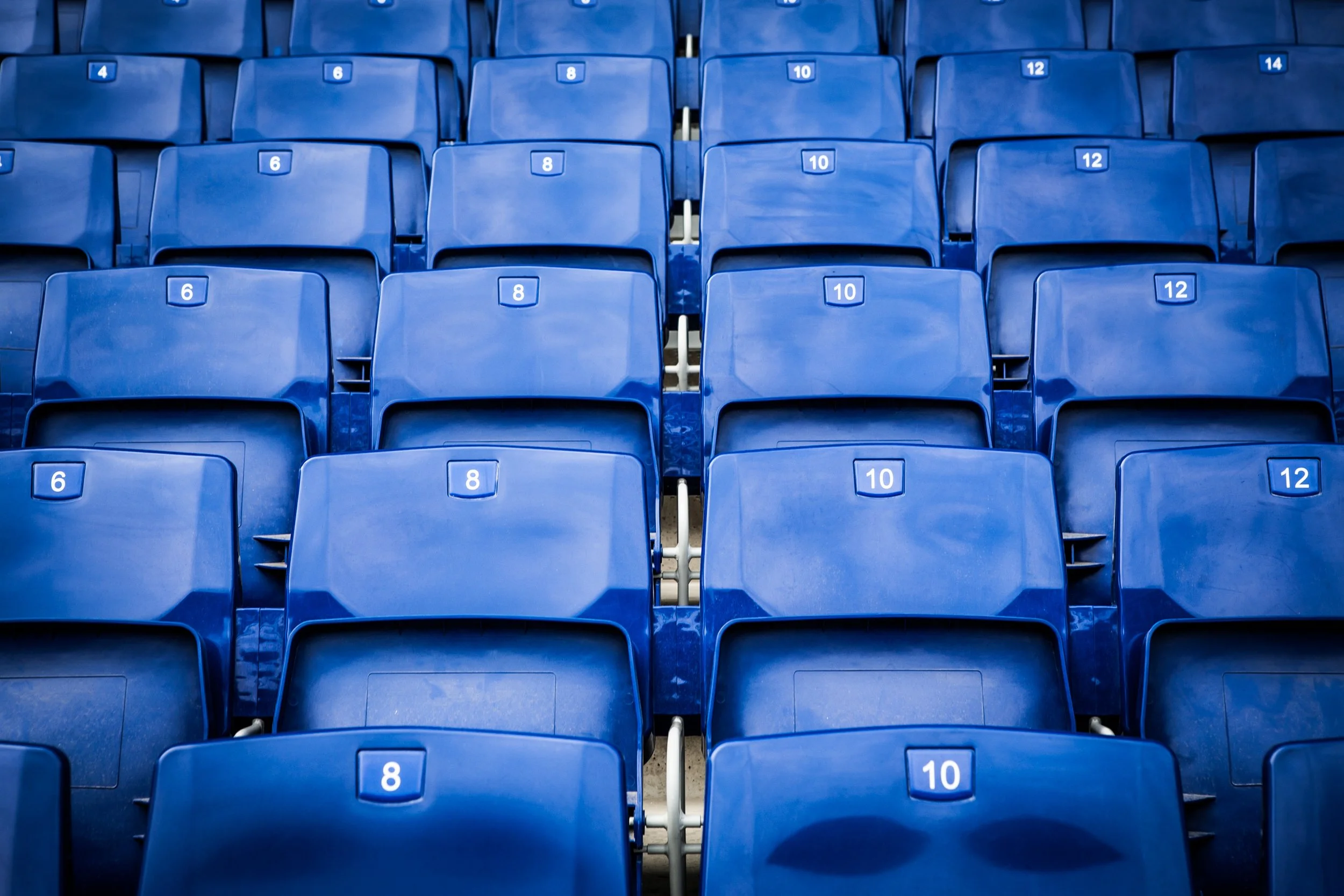 Multiple rows of blue stadium seats with numbered labels.