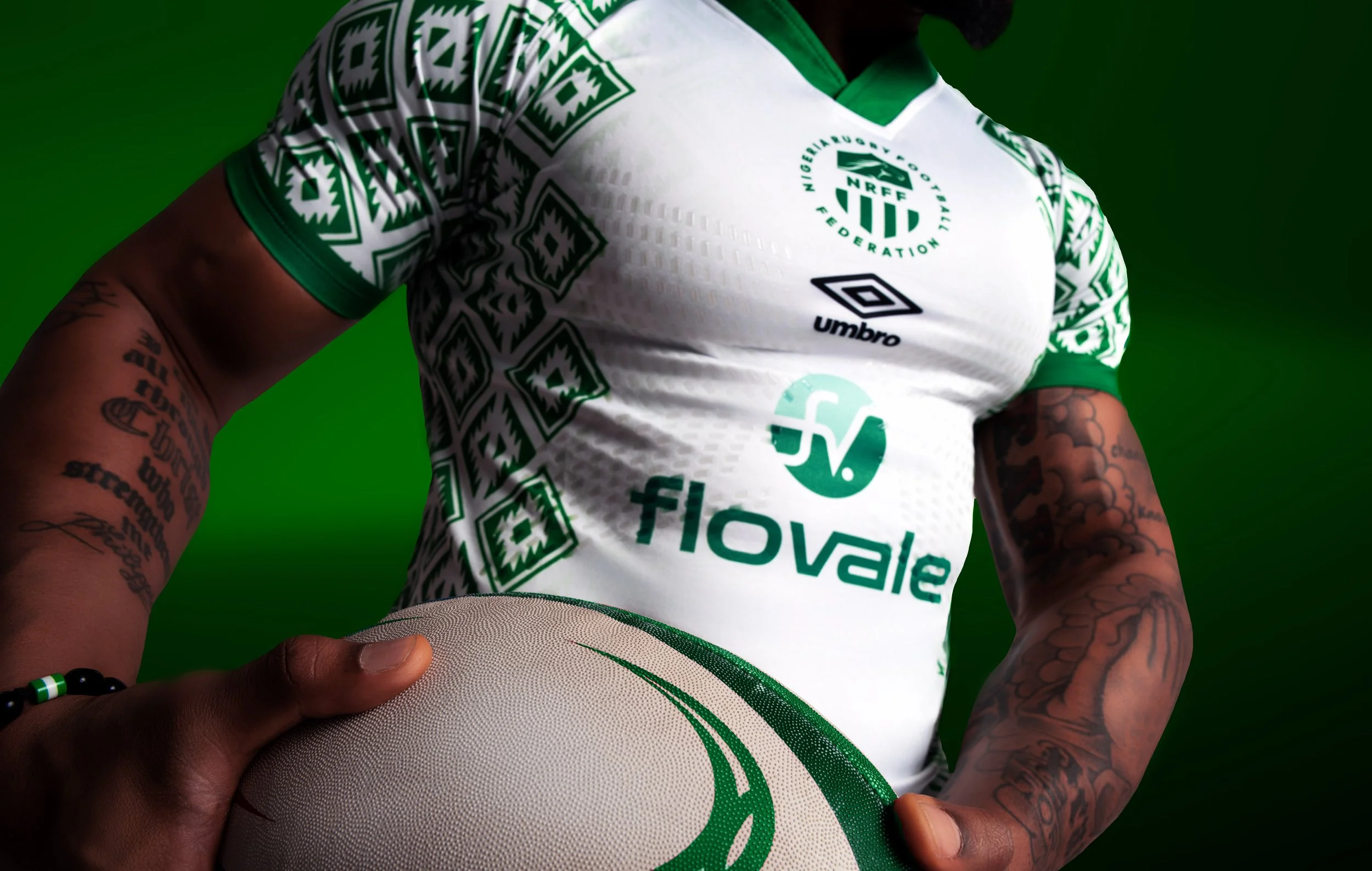 Person holding a soccer ball, wearing a white and green Nigeria national football team jersey with sponsor logos, green background.