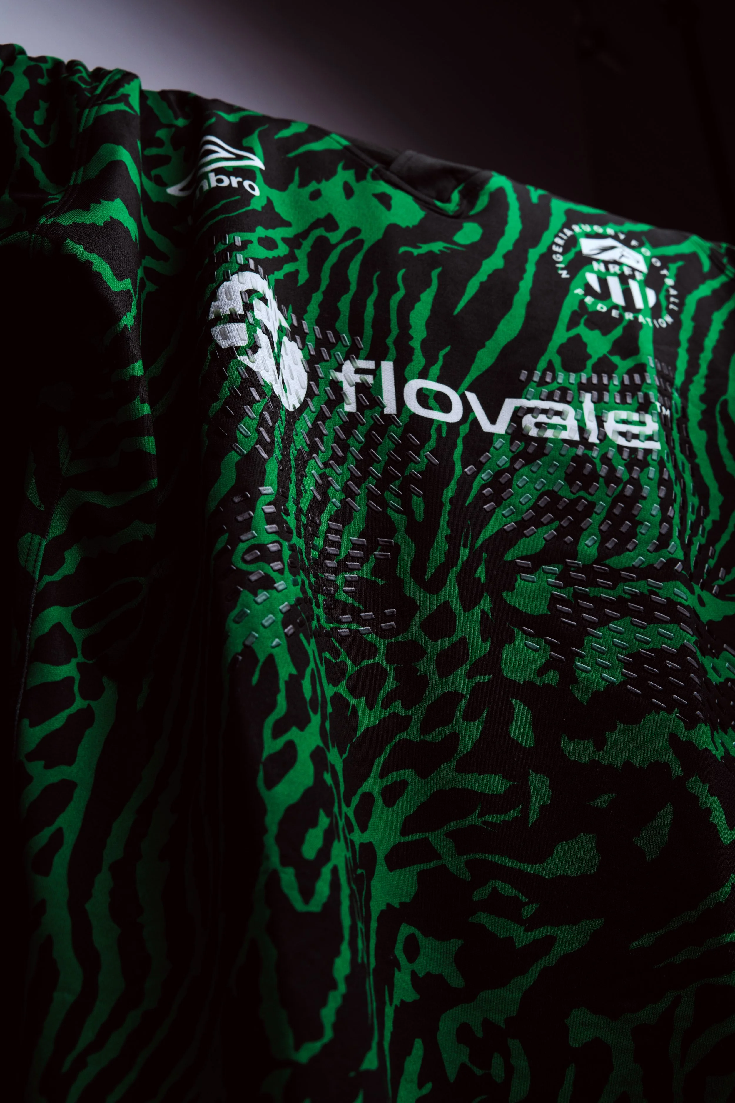 Close-up of a black and green patterned sports jersey with sponsor logos, including 'beyond,' and a patch with the NFL shield logo.