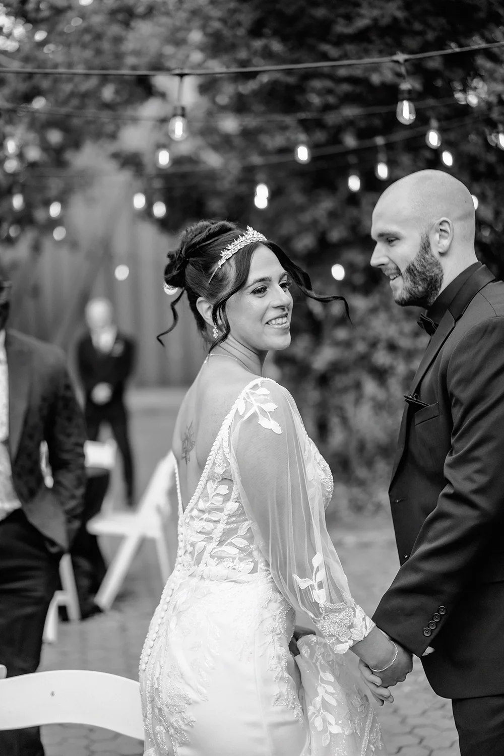 A black and white photo of a bride and groom dancing under lights