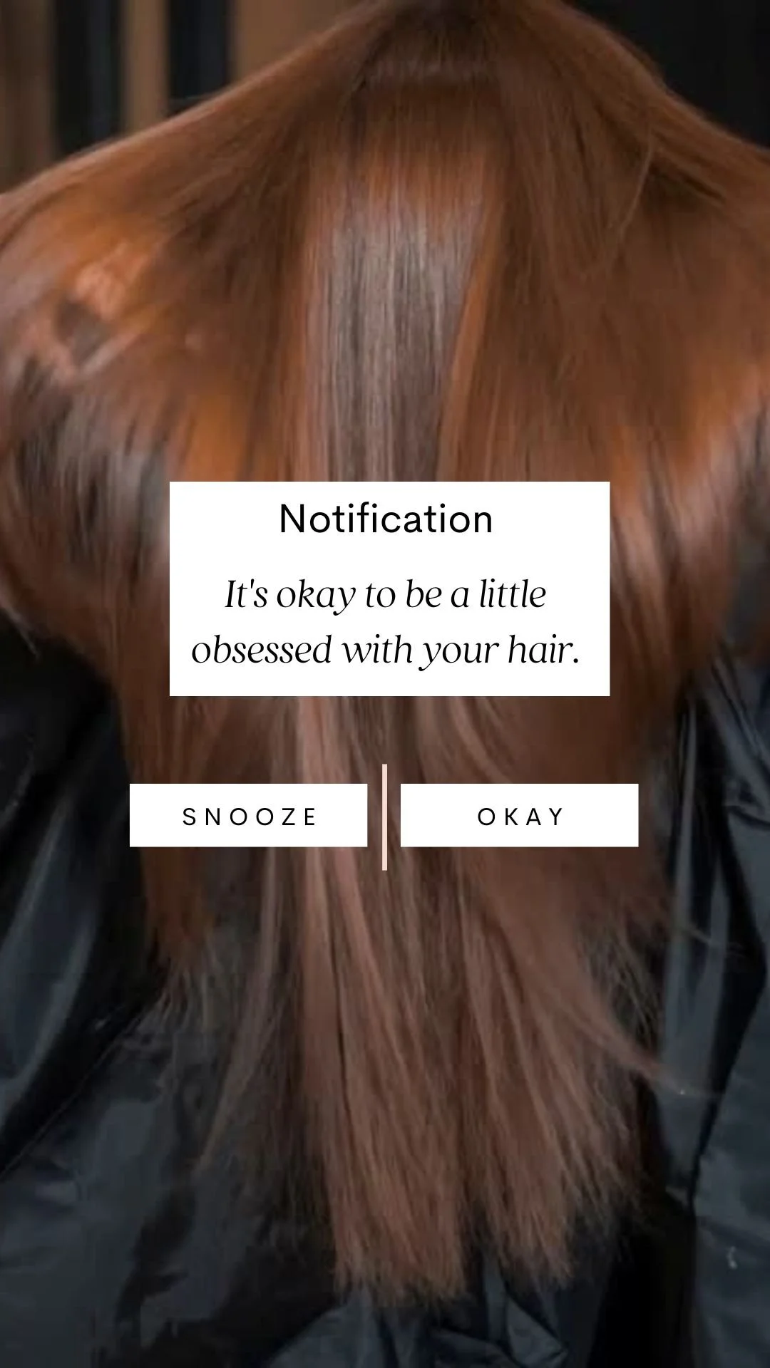 A person with straight, reddish-brown hair covering their face. A notification overlay on the image says, 'It's okay to be a little obsessed with your hair,' with options to snooze or okay the notification.