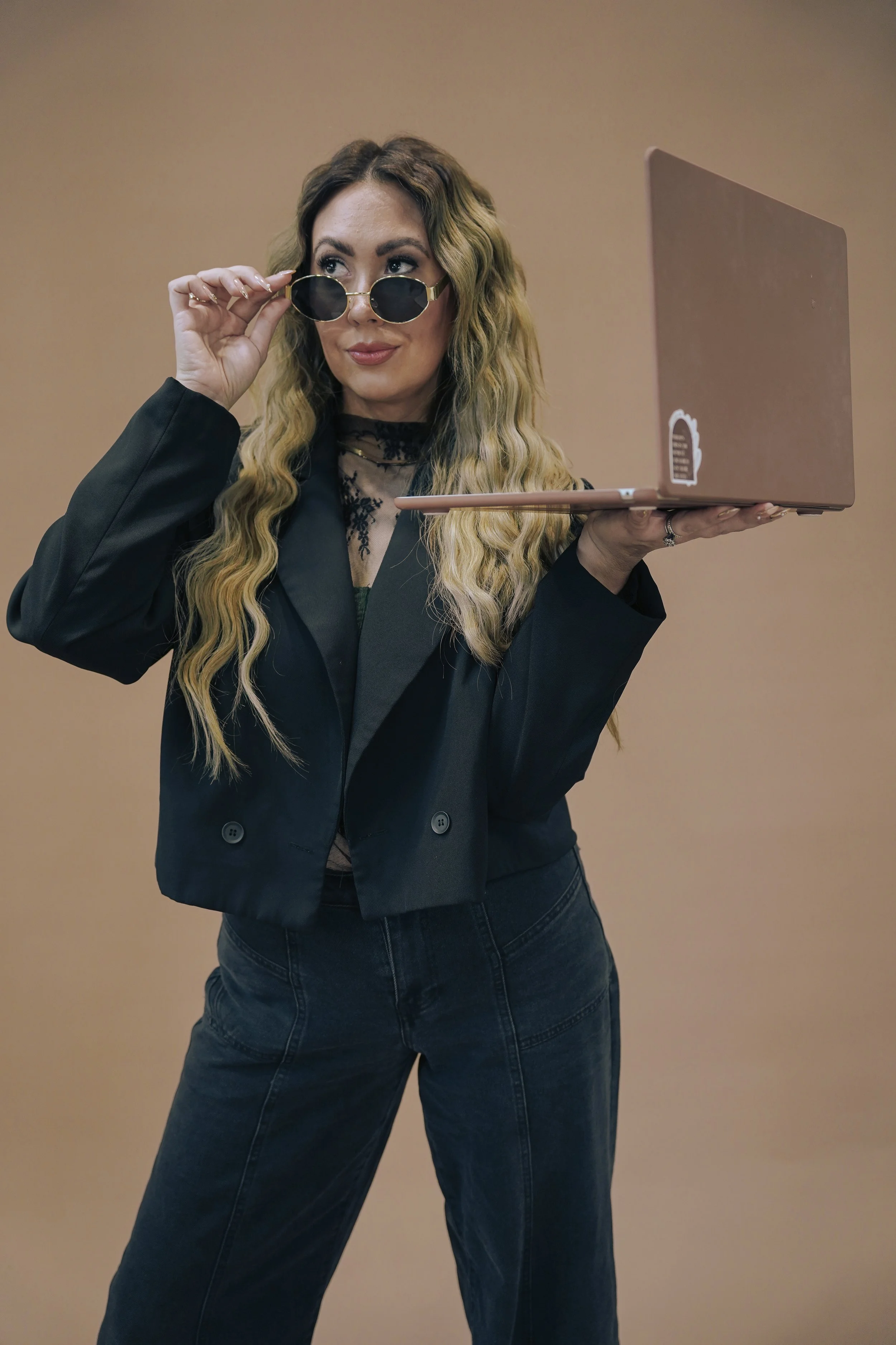 Hair stylist and business owner of The Ember Room in Clermont, Florida, holding a laptop during a salon brand photoshoot.