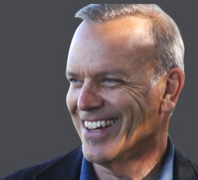 Close-up of a smiling middle-aged man with short, light-colored hair and blue eyes.
