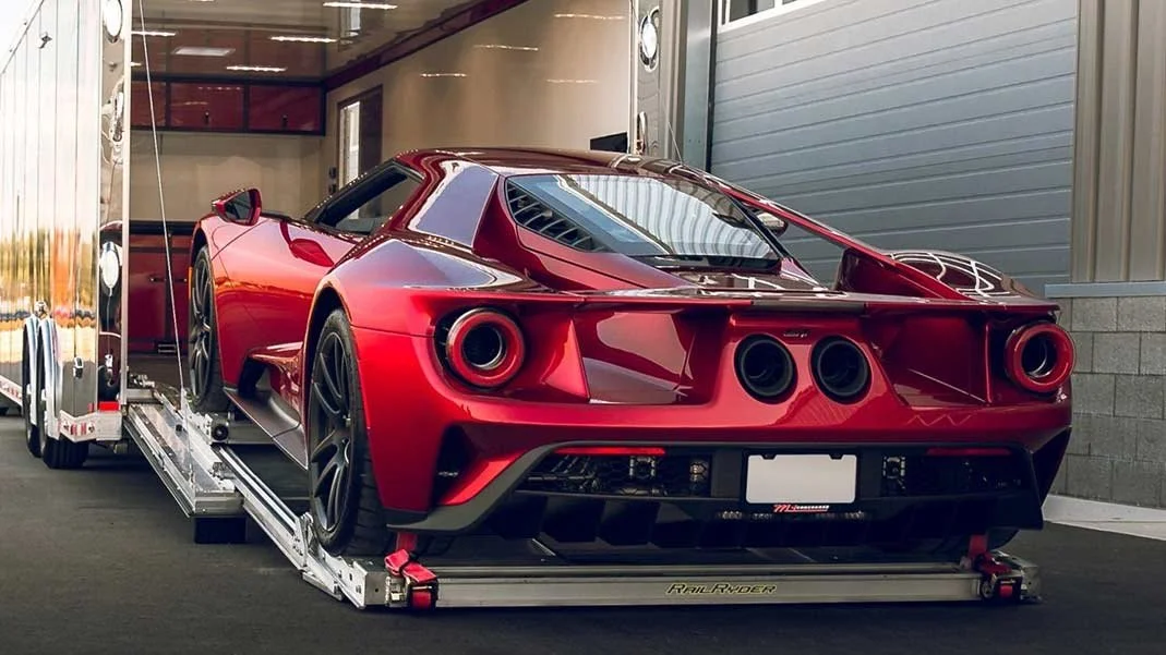 Red race car on a transport trailer in a garage or storage area.