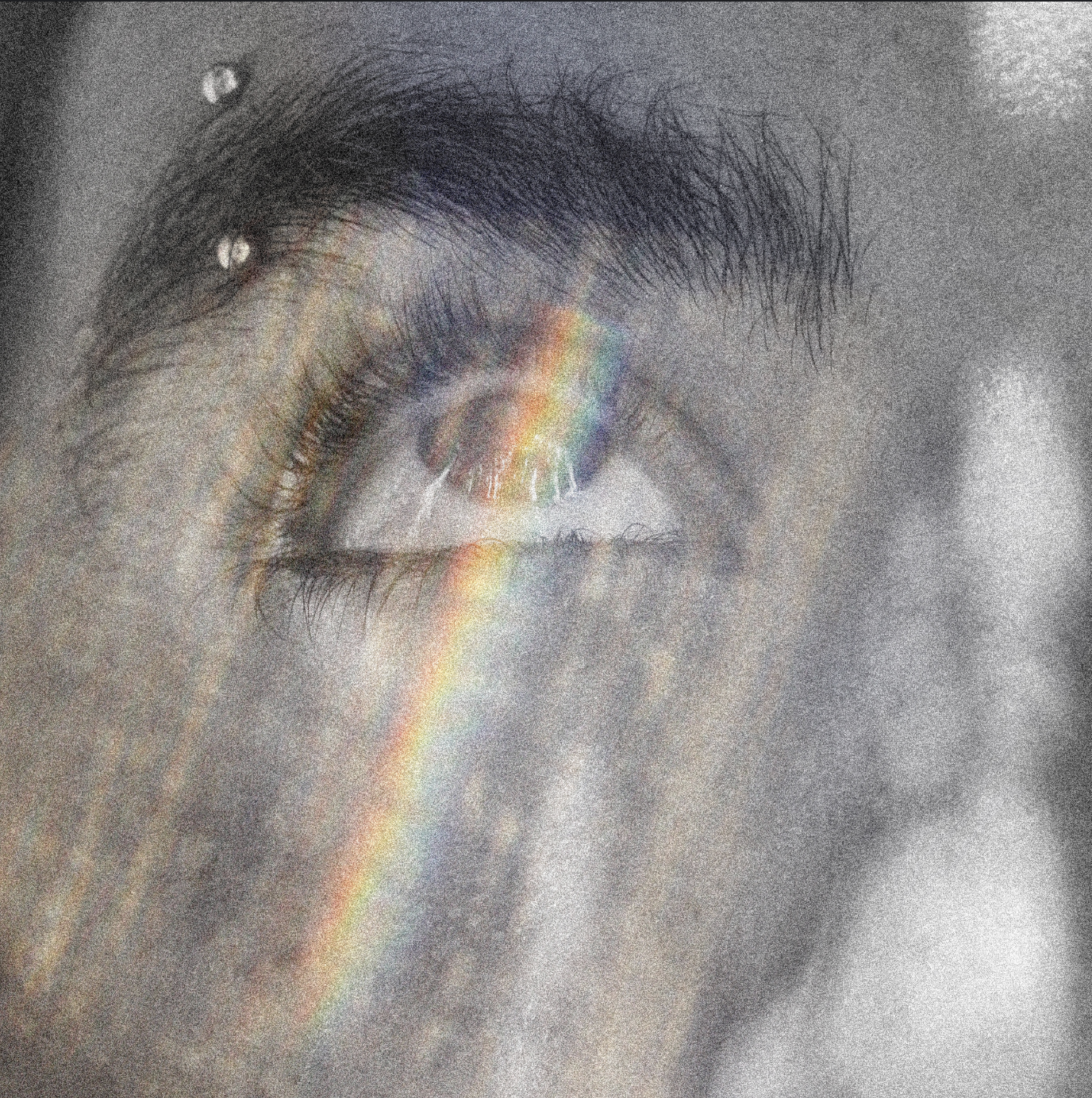 Close-up of a closed human eye with a rainbow reflecting on the eyelid, dark eyelashes, and a faint gray background.