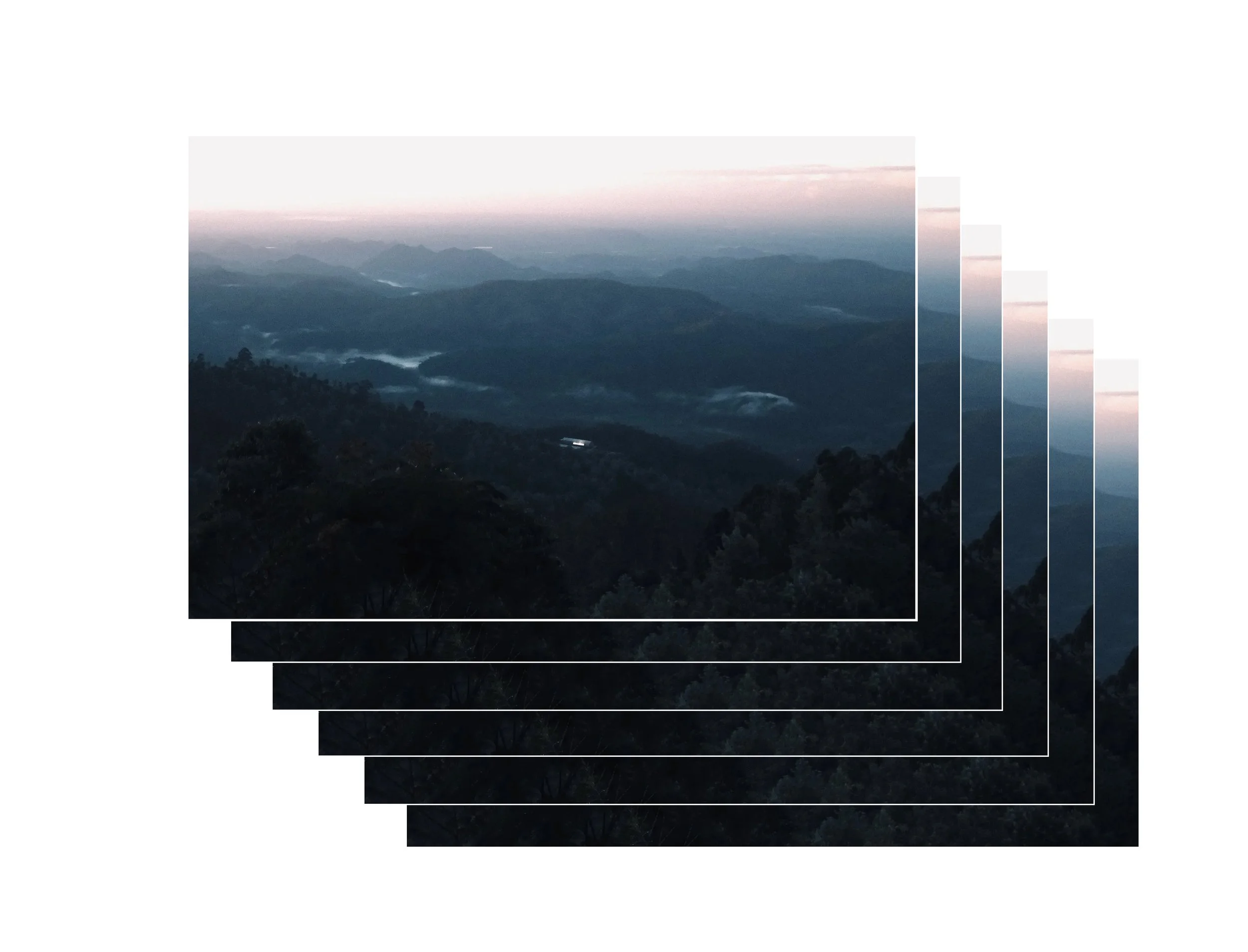 Mountain landscape during sunrise or sunset with layers of mountains, fog, and a pastel sky.