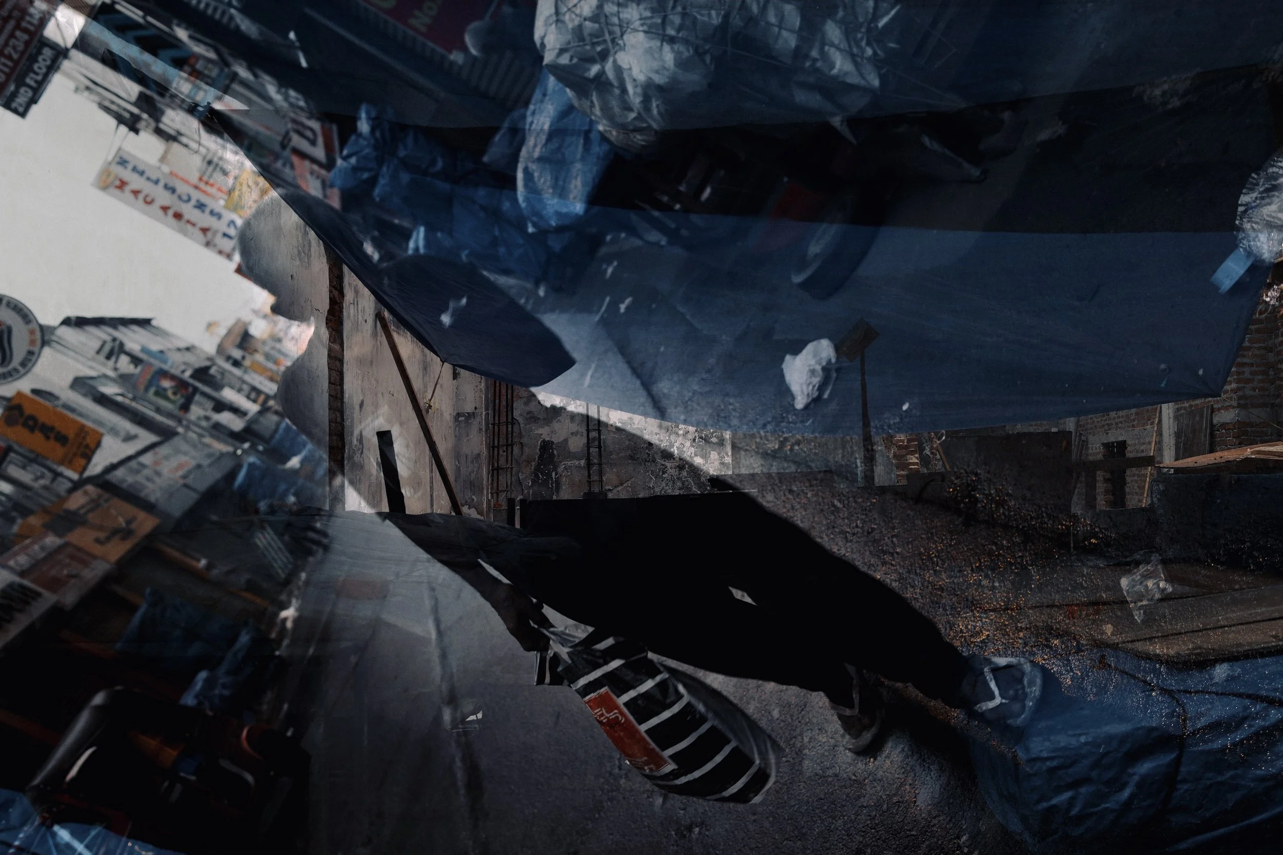 Construction site with wrapped building materials and a worker with a striped bag in the foreground.