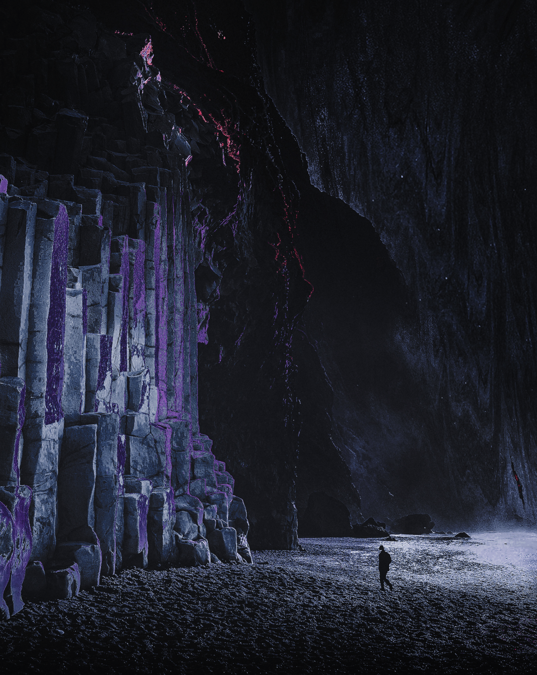 A person standing inside a large dark cave with towering rock formations illuminated by purple and blue lights, and waves crashing at the entrance.