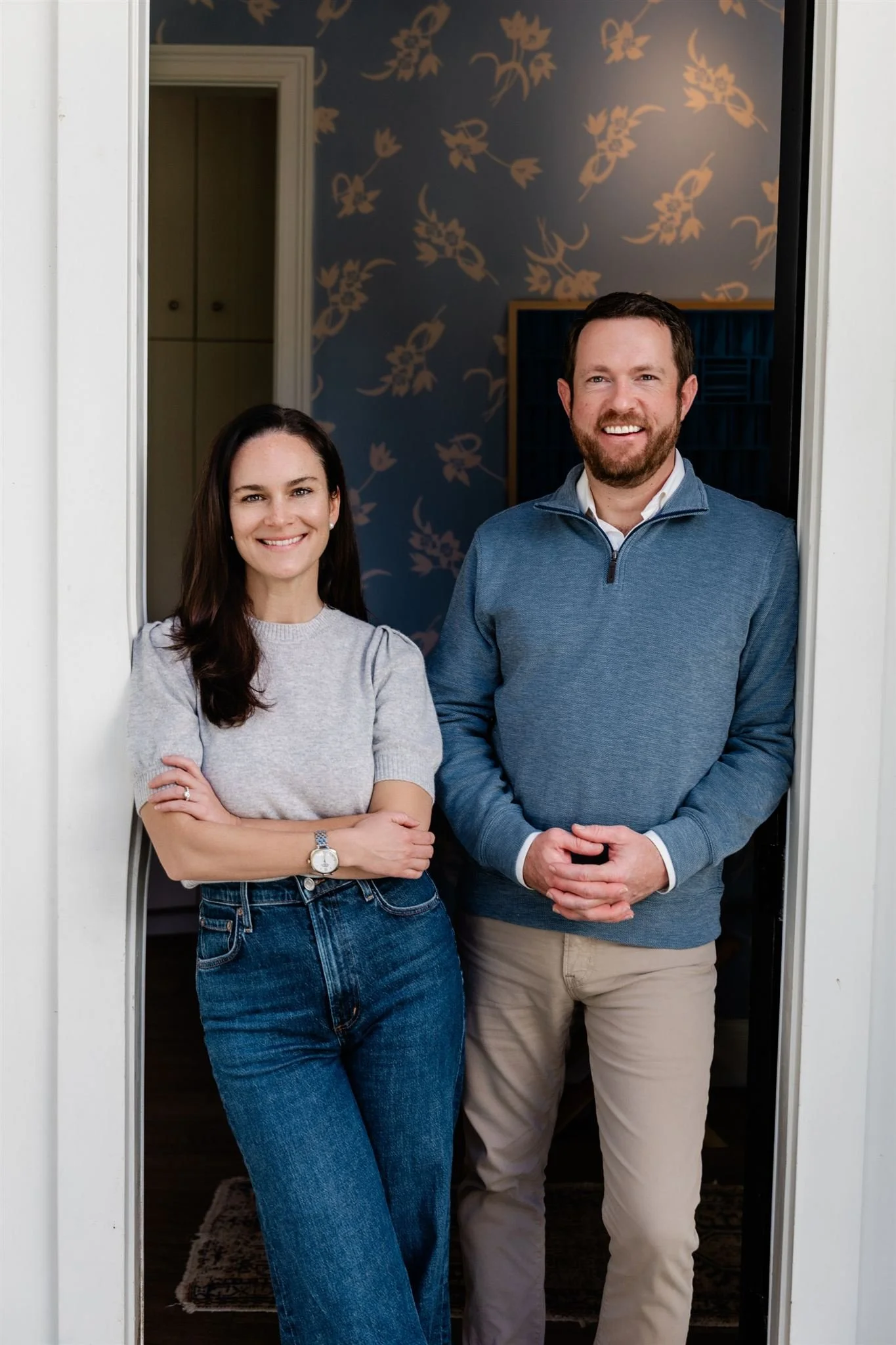 A man and a woman standing in a doorway, smiling at the camera.