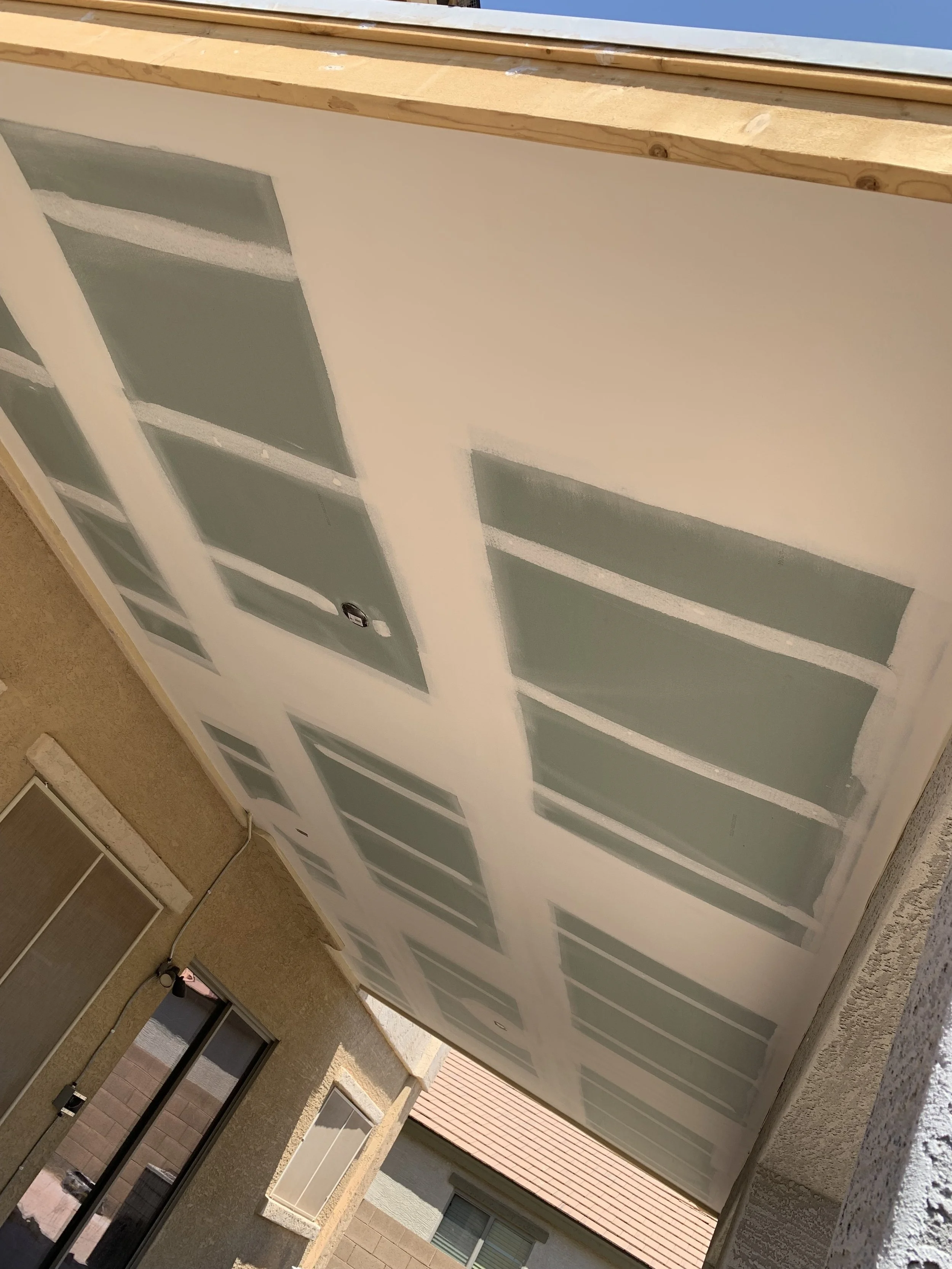 Ceiling under construction with drywall and joint compound, showing taped seams.