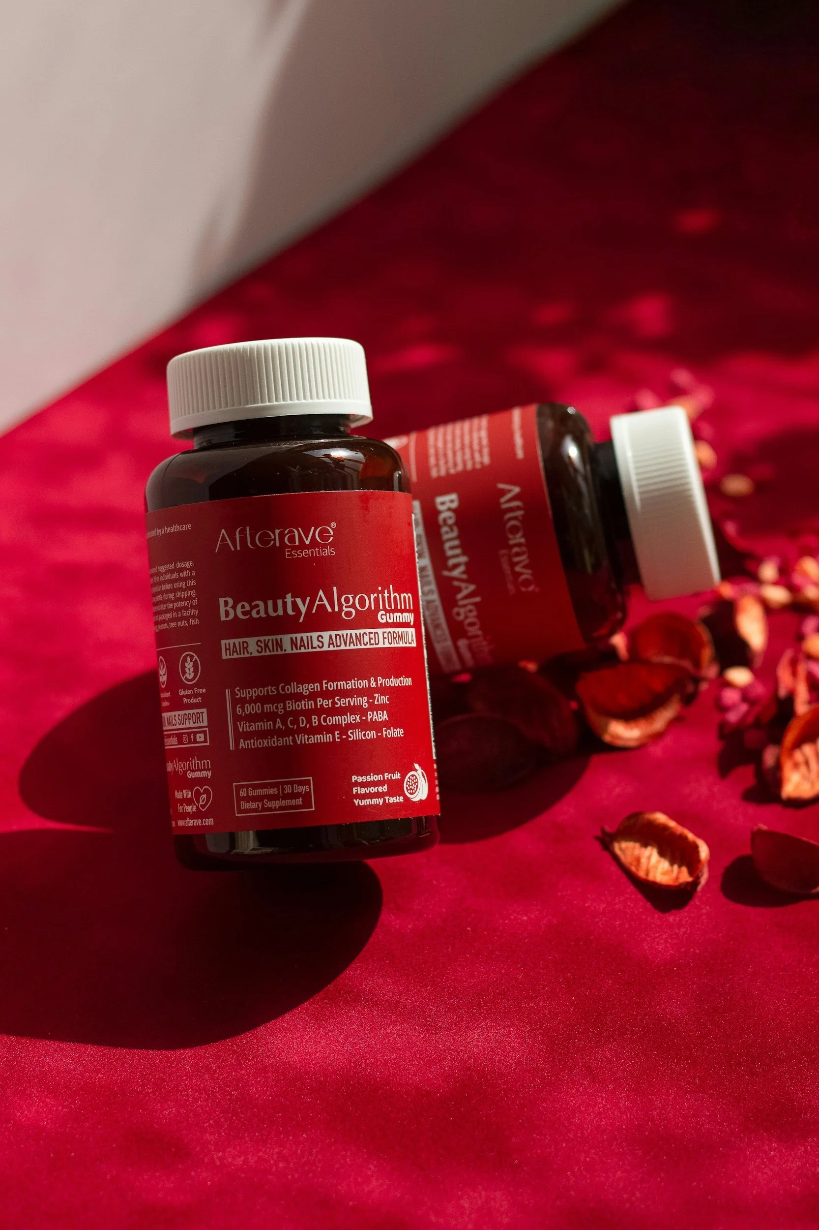 Three brown bottles of supplement labeled 'Fjord Strong Omega 3' with mountain scenery on a pink background, partially obscured by green plant leaves in the foreground.