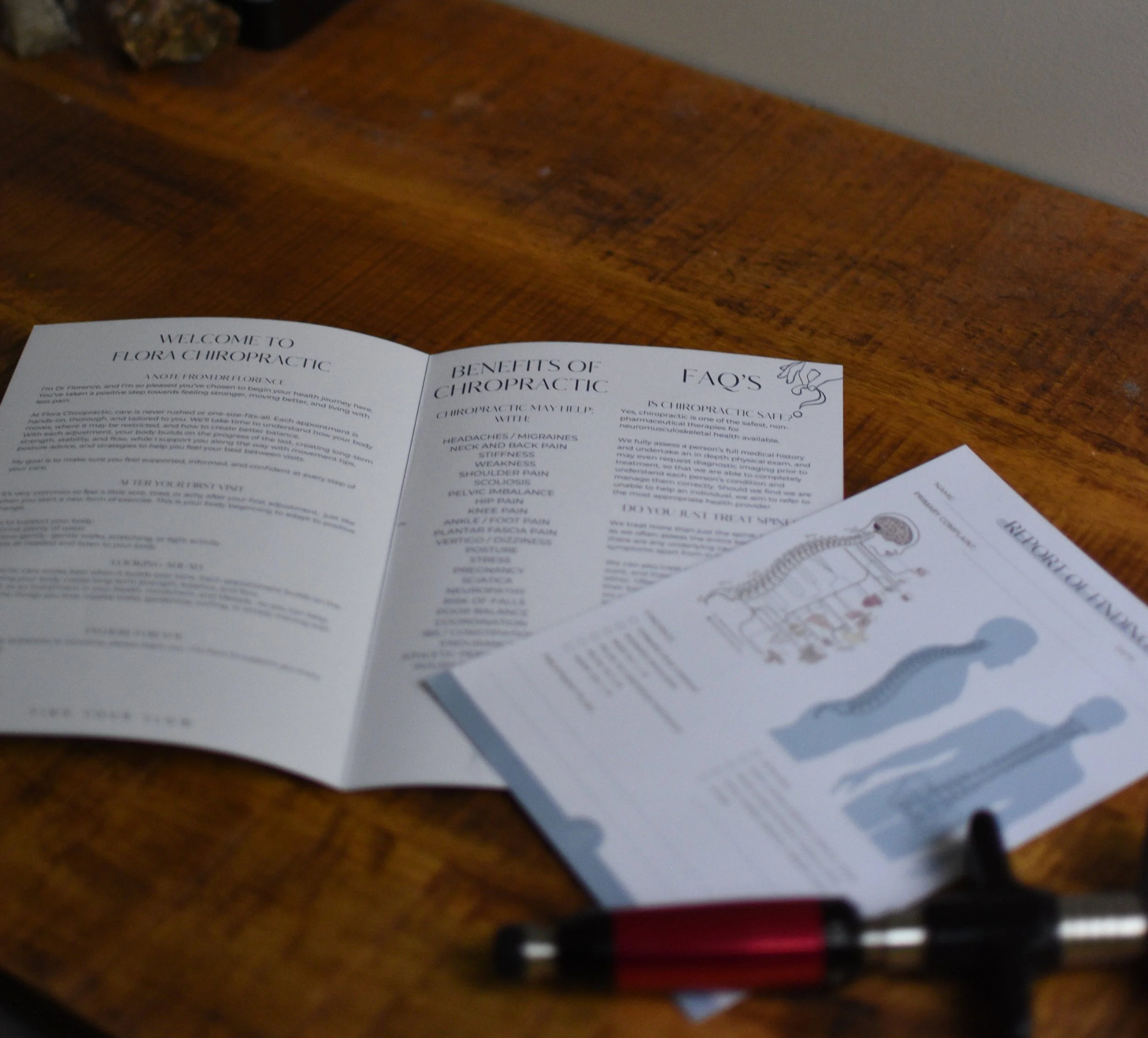 Close-up of a folded informational pamphlet on a wooden surface, with text about chiropractic benefits and FAQs.
