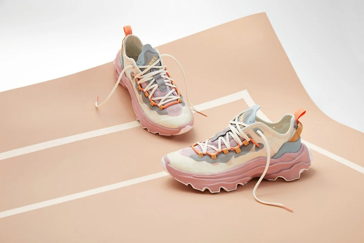 Colorful athletic sneakers with pastel shades, placed on a peach-colored surface with white lines, resembling a running track.