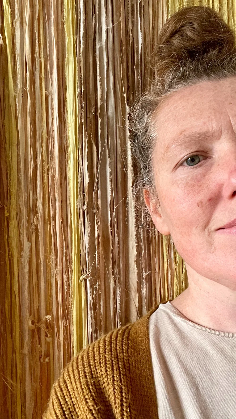 Close-up of a woman's face on the right side of the image, wearing a brown sweater and a beige shirt, with a textured wooden background.