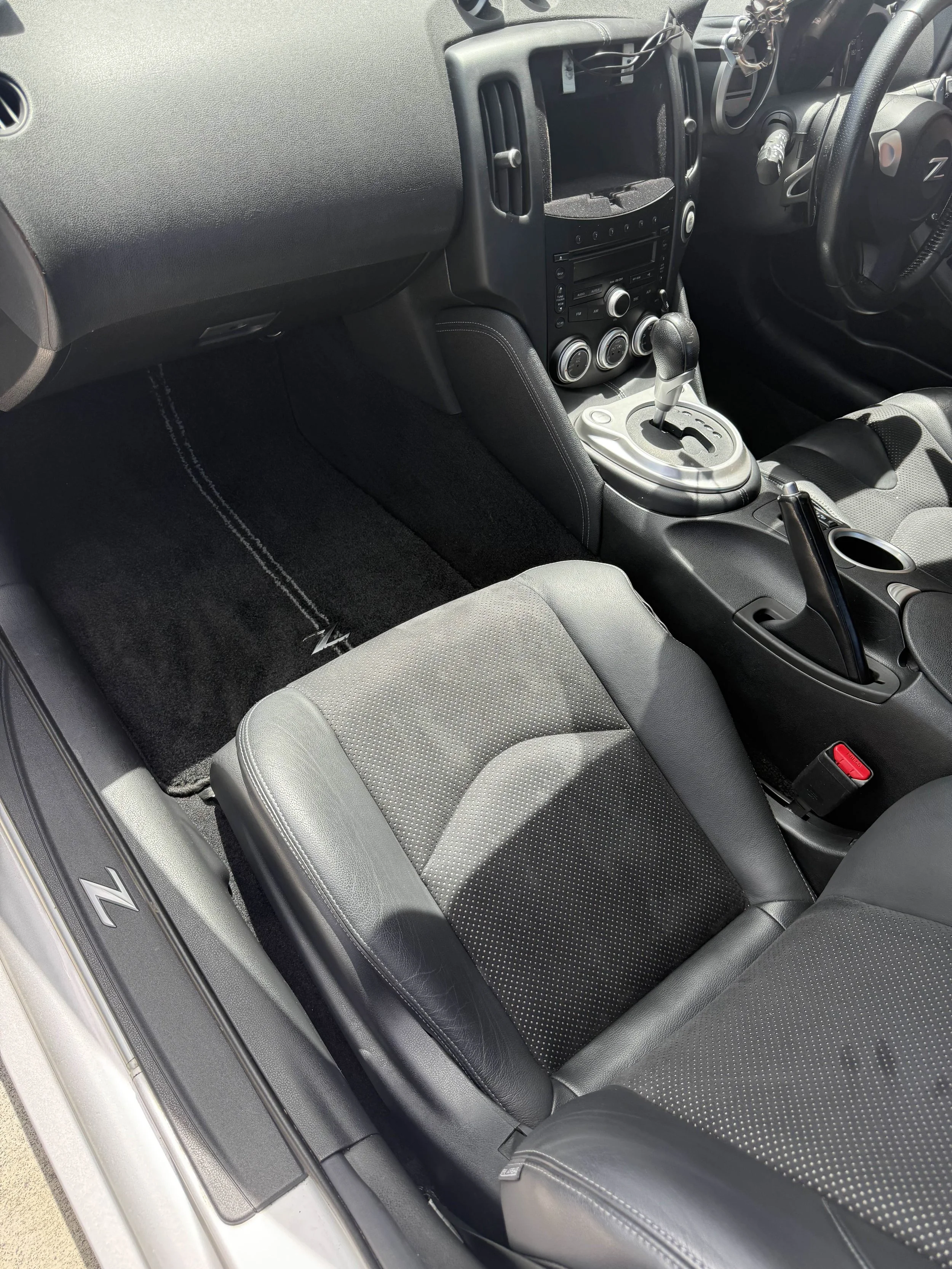 Interior of a car showing the front passenger seat, center console with gear shift, cup holder, and dashboard controls.