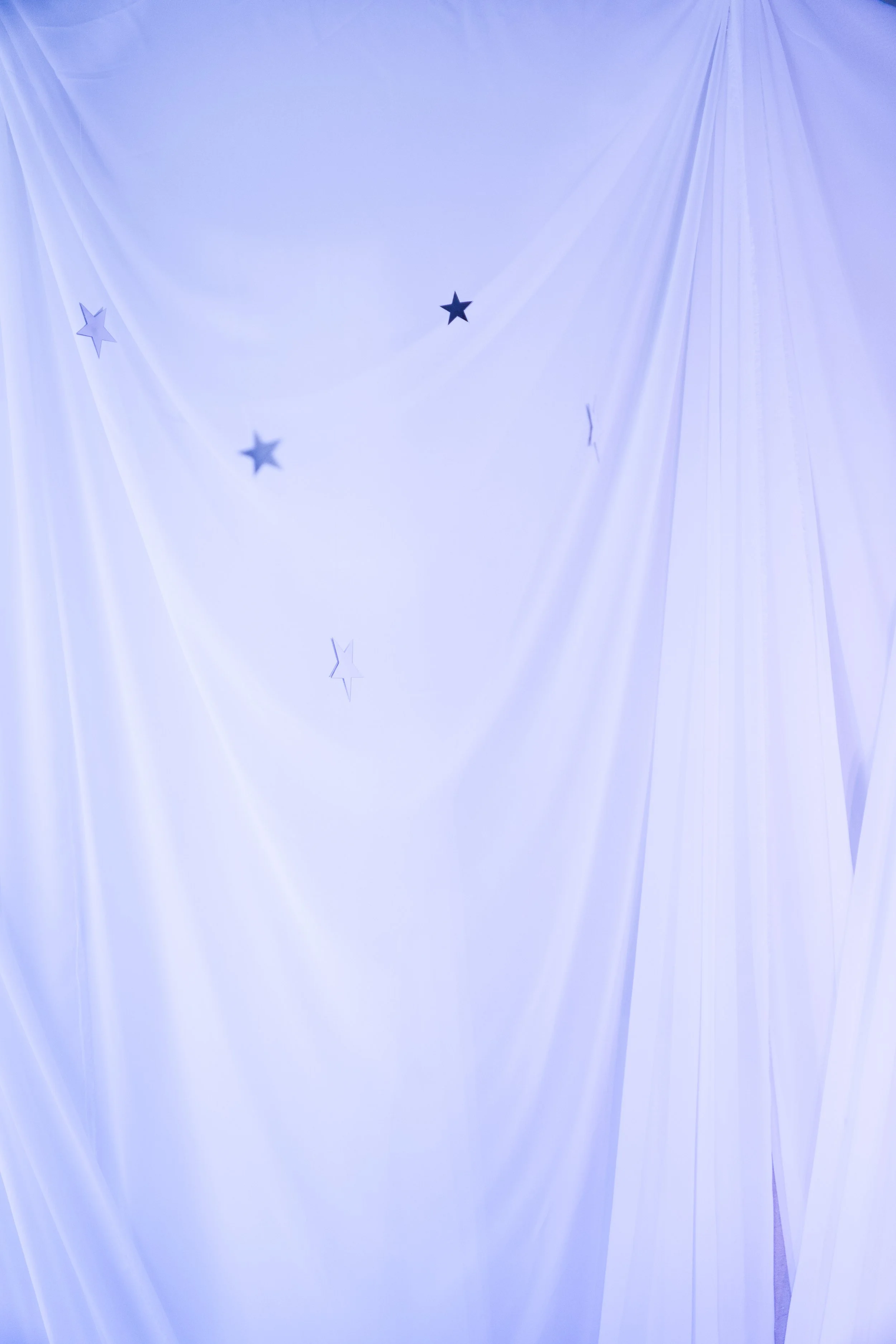Light blue fabric background with small dark and light star-shaped cutouts.