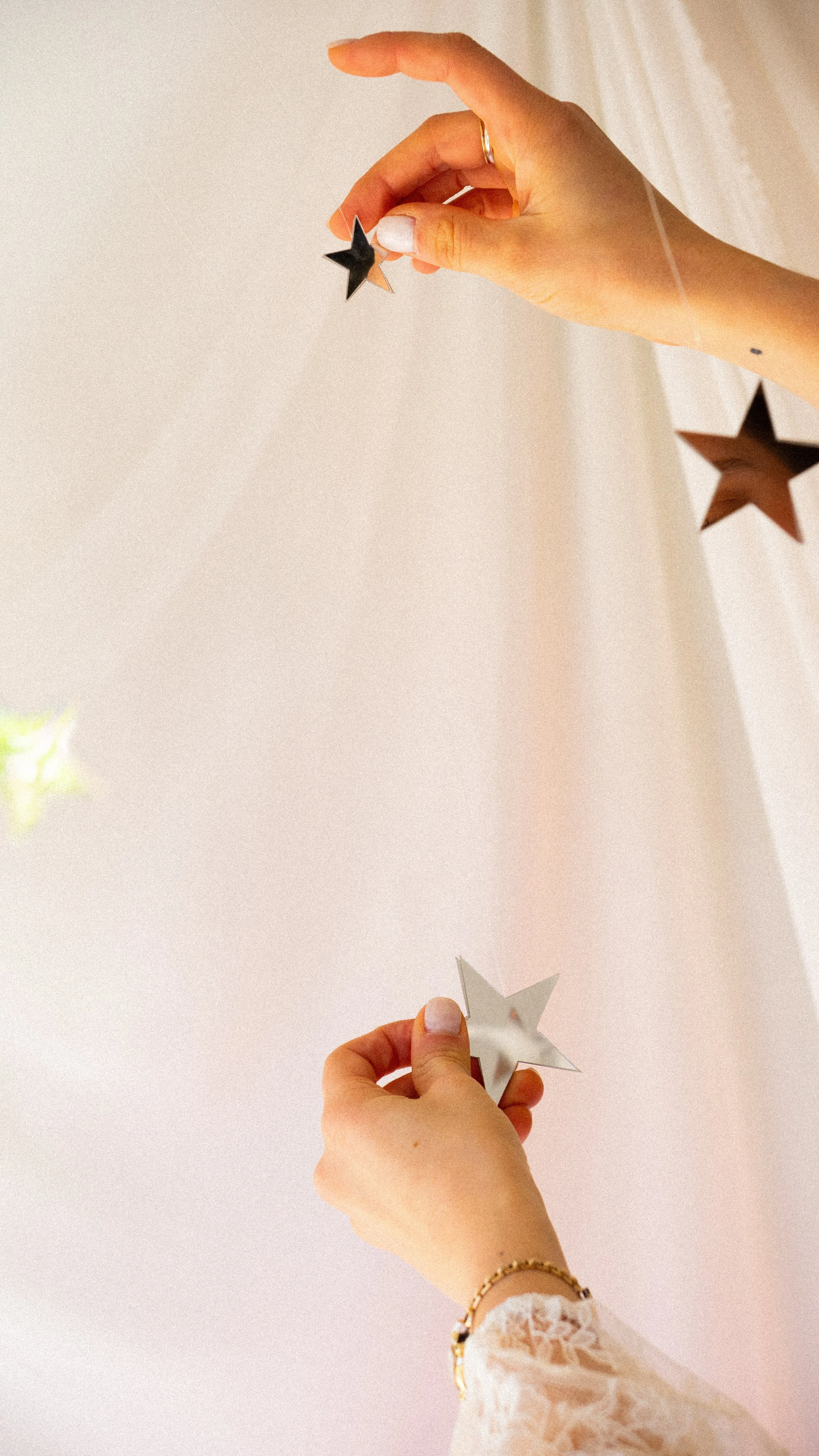 Person holding metallic star-shaped decorations, hanging from the ceiling.
