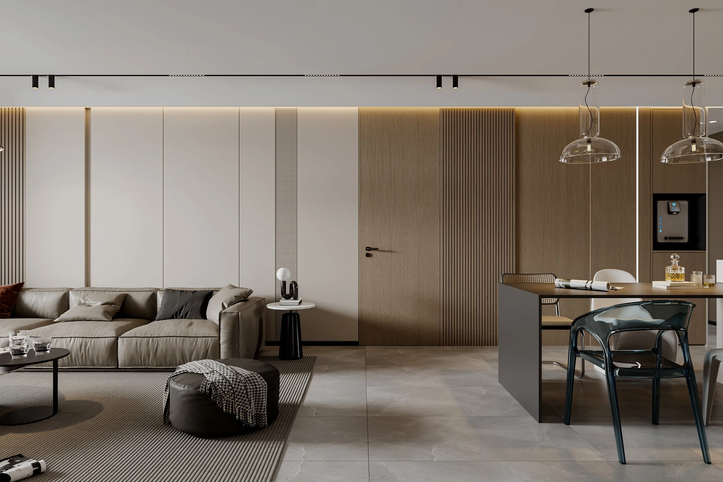 Modern living room and dining area with beige sofa, circular coffee table with glasses, black pouf with blanket, side table with lamp, dining table with chairs, glass pendant lights, wooden wall panels, built-in electronic device, and a gray kitchen island.