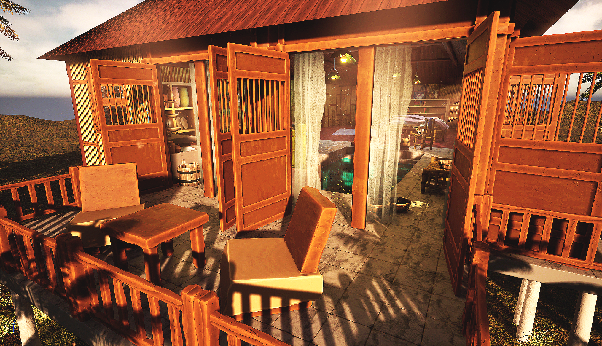 View of a wooden patio with chairs and a railing, attached to a house with open doors revealing a cozy indoor space with books and lighting, at sunset.