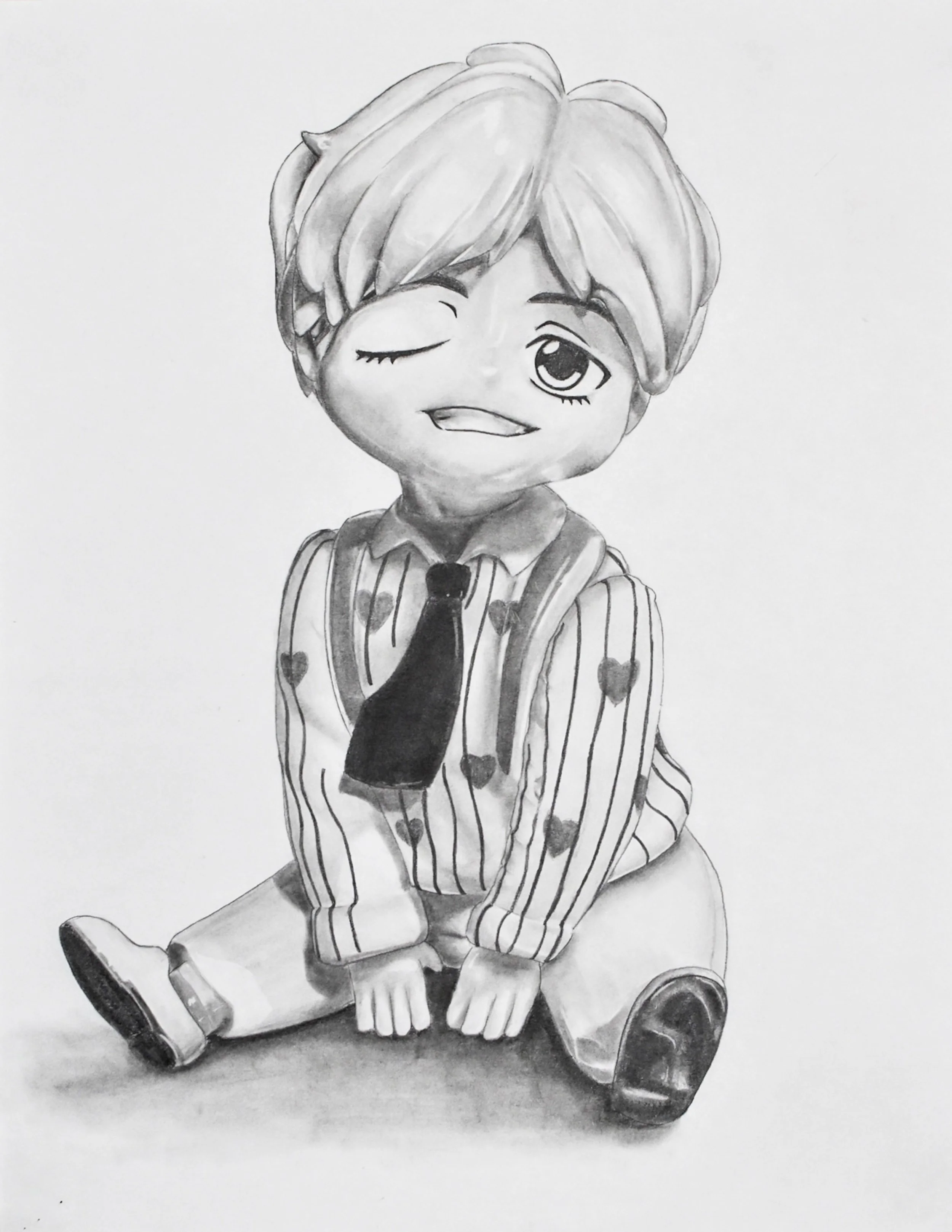 A black and white drawing of a cartoon boy with blond hair, sitting on the ground with legs crossed, winking and smiling. He wears a striped shirt with hearts, a tie, and sneakers.