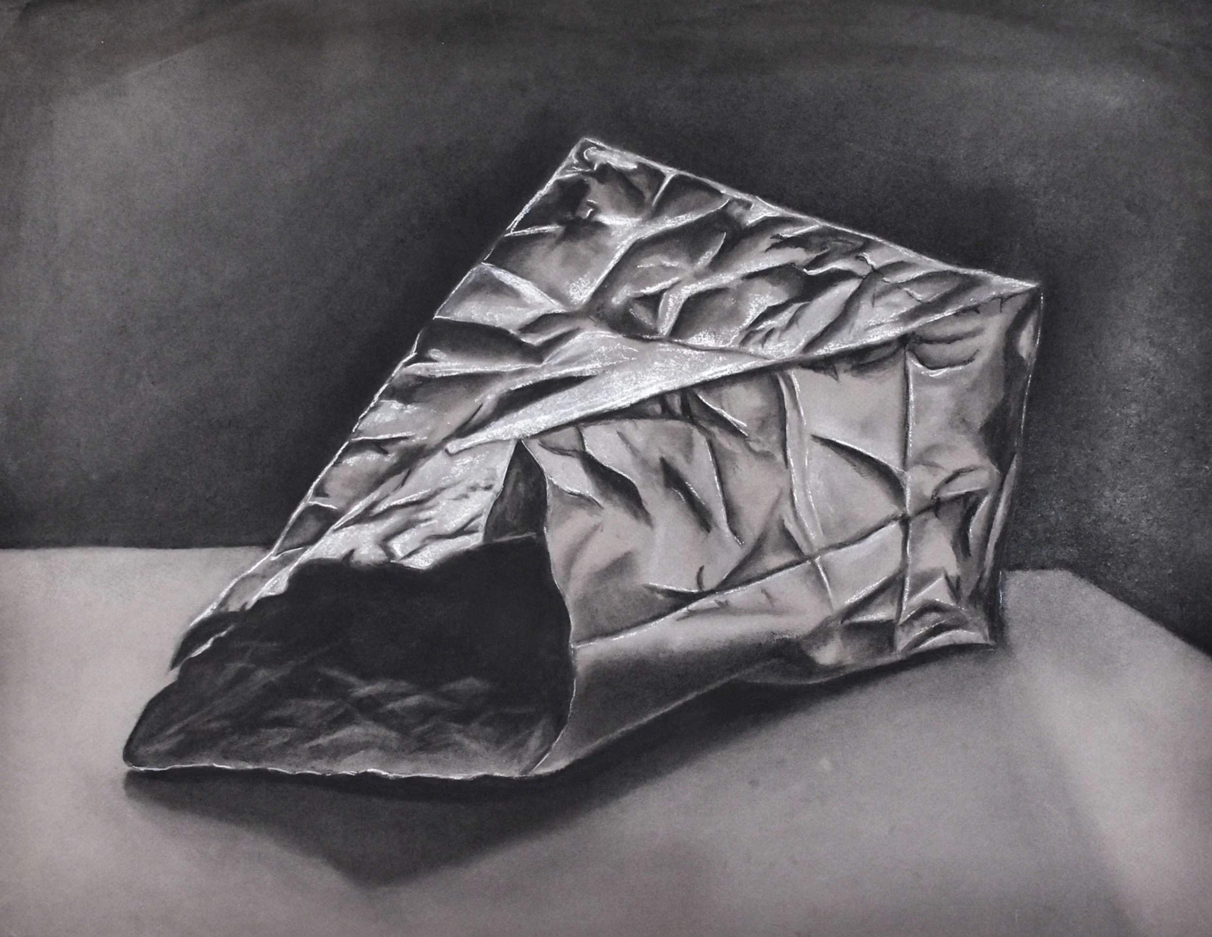 A crumpled metallic foil bag on a flat surface with a dark background.