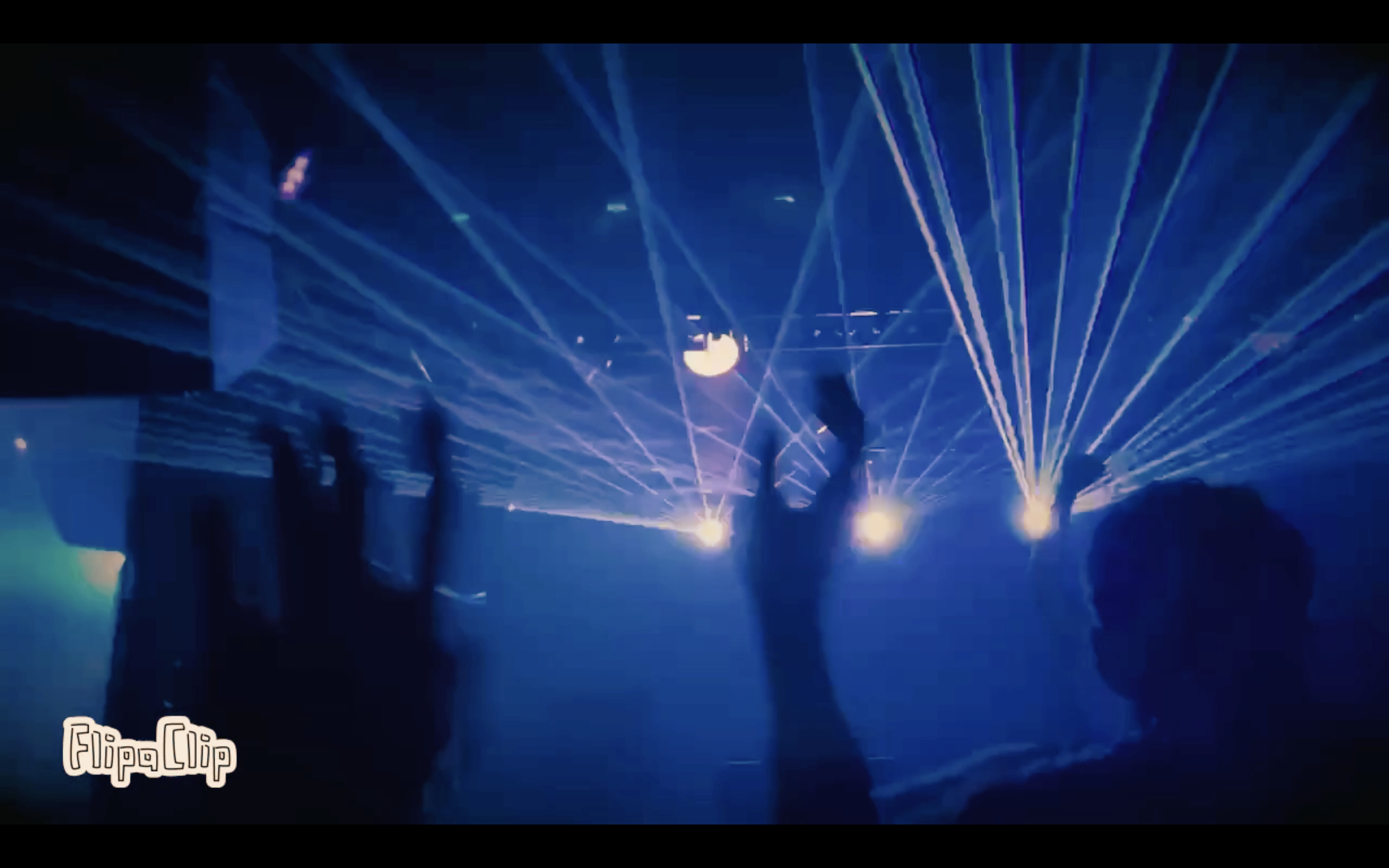 People dancing at a nightclub with blue laser lights and a disco ball.