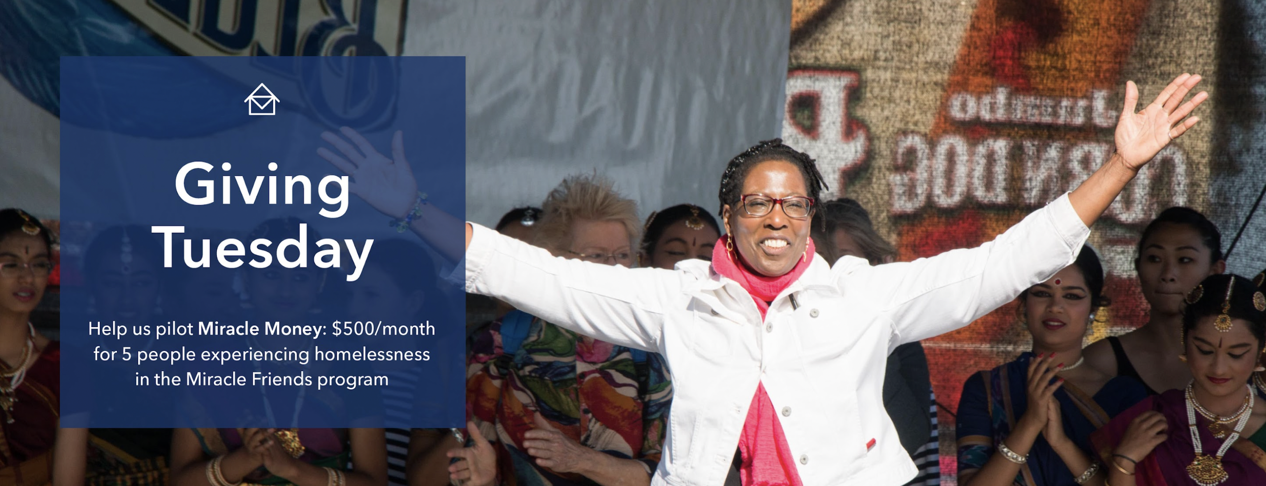 A diverse group of people with the woman in the front wearing glasses, a white jacket, and a pink scarf, raising her arms in celebration at an outdoor event with a large screen displaying text in the background. Overlaid text reads: "Giving Tuesday. Help us pilot Miracle Money: $500/month for 5 people experiencing homelessness in the Miracle Friends program."