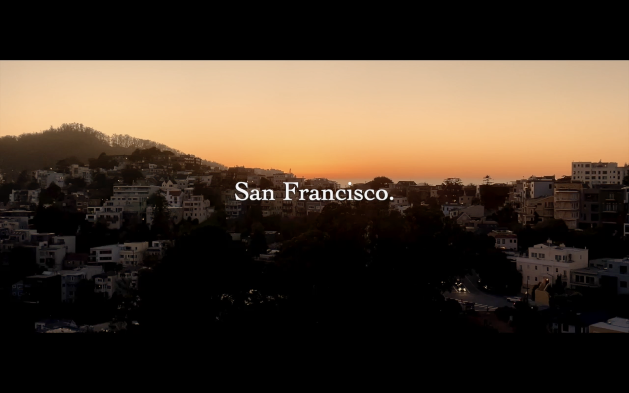 Sunset over San Francisco with a cityscape of buildings and hills.