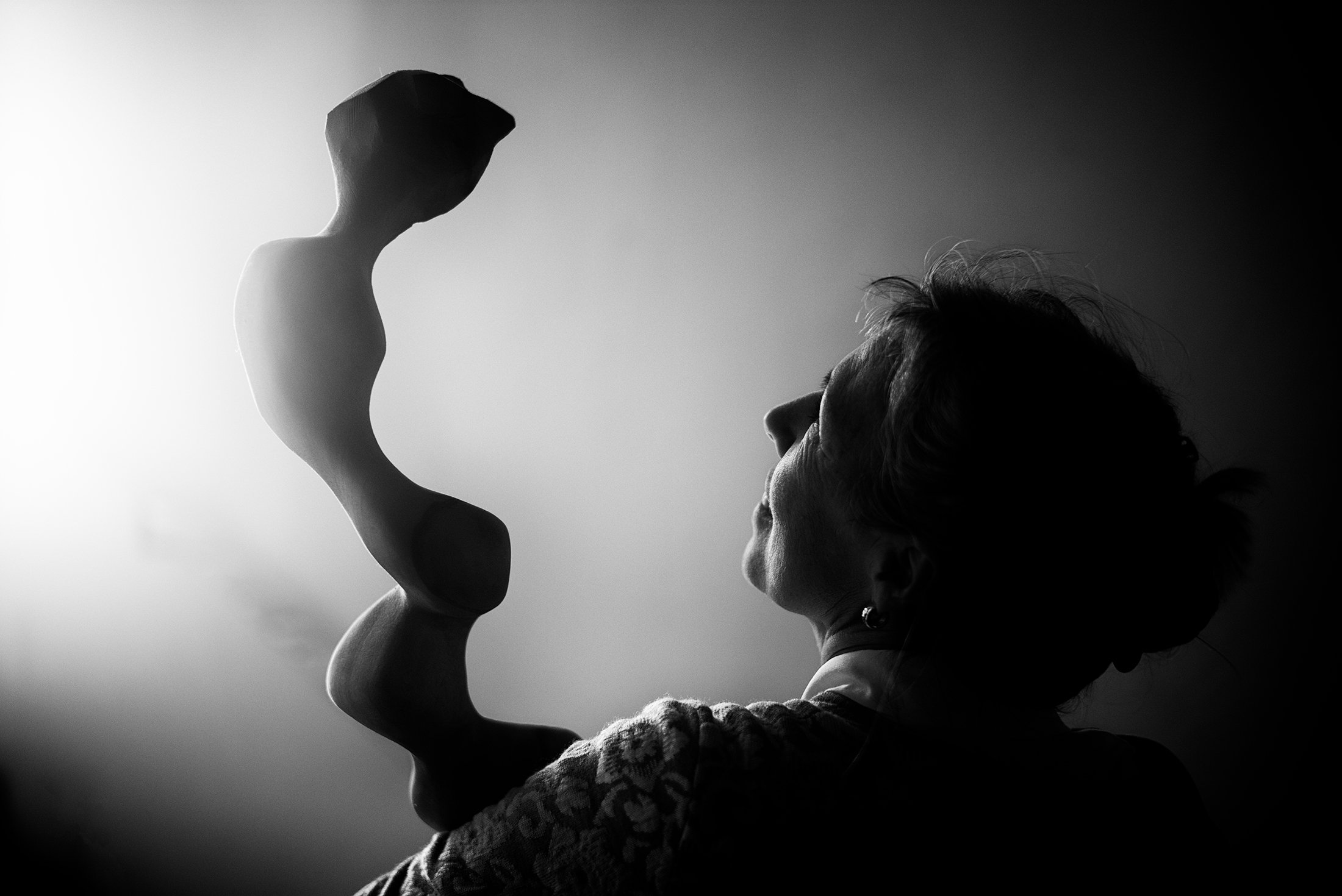 Eine Frau hält eine Skulptur, die eine menschliche Figur darstellt, in schwarz-weiss