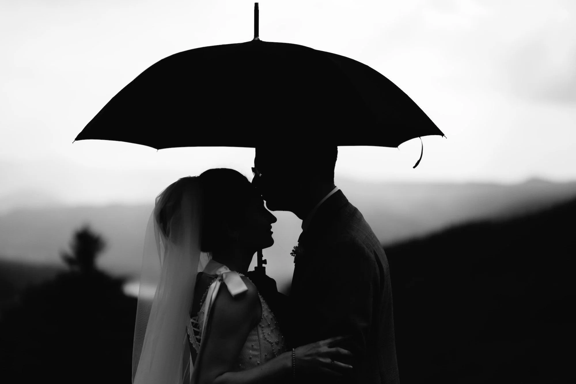 Silhouette of a bride and groom sharing an intimate moment under an umbrella during a moody and romantic West Yorkshire wedding